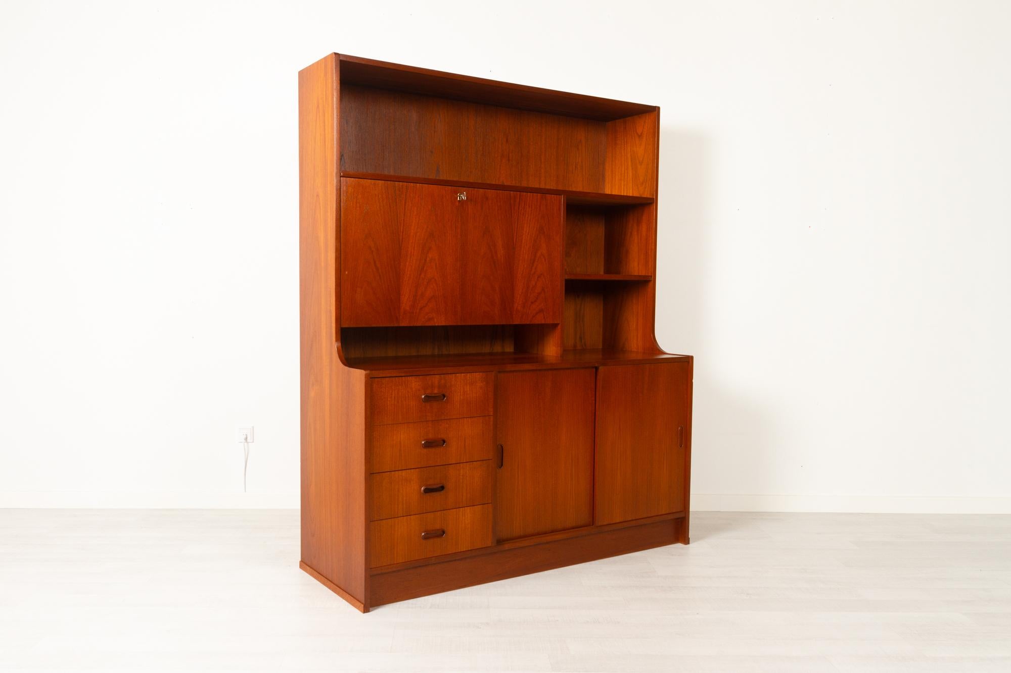 Vintage Danish teak bookcase 1960s
Classic Danish Mid-Century Modern wall unit in teak. Drawer section with four drawers, sculpted pulls in solid teak. Large cabinet with double sliding doors. Bar cabinet with lockable drop down door and one shelf.