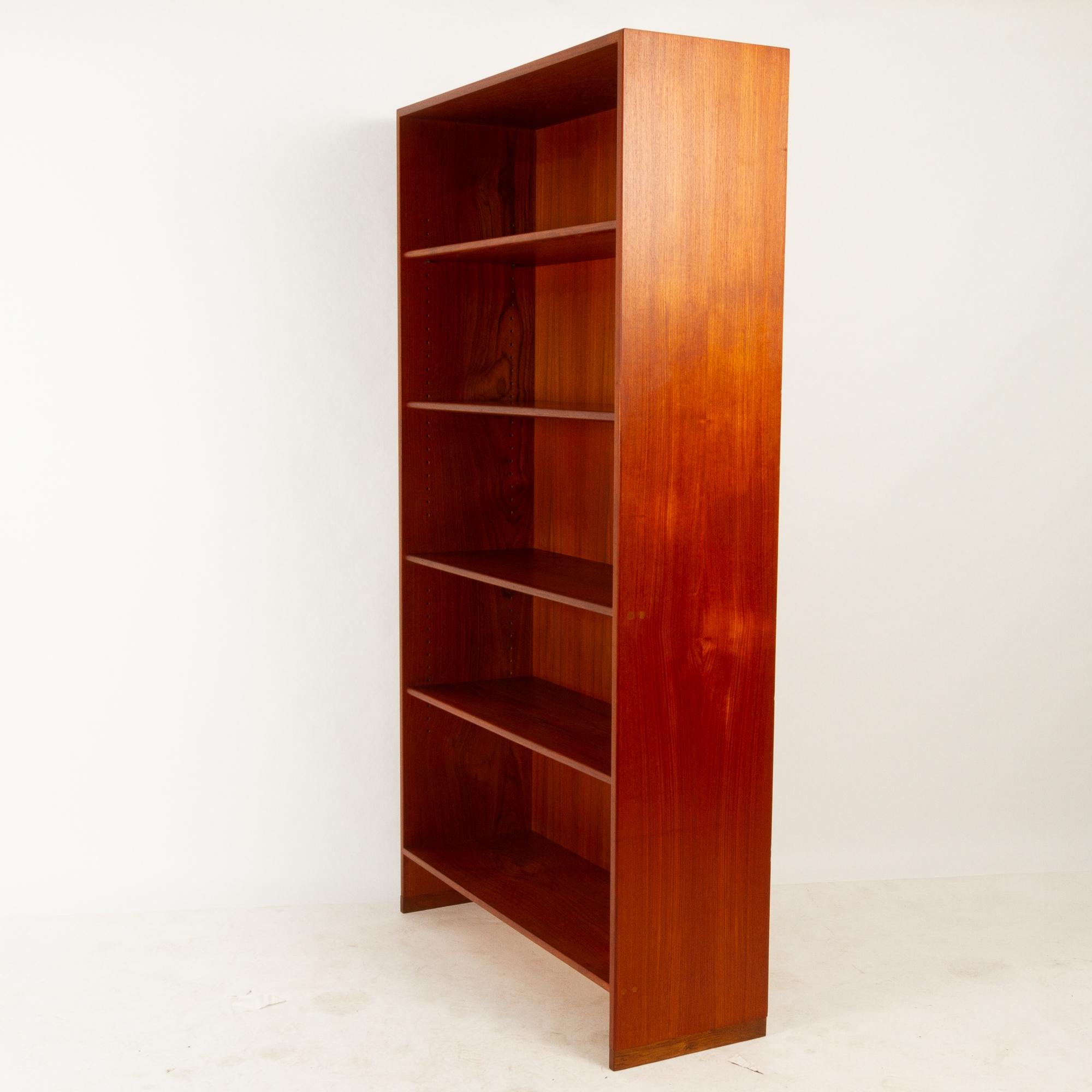 Tall and spacious teak bookcase designed by famous Danish architect Hans J. Wegner and made by Ry Møbler.
In the rare model with body made with teak veneer and shelves edged with solid teak profiles. It stands on feet made of solid oak. Three