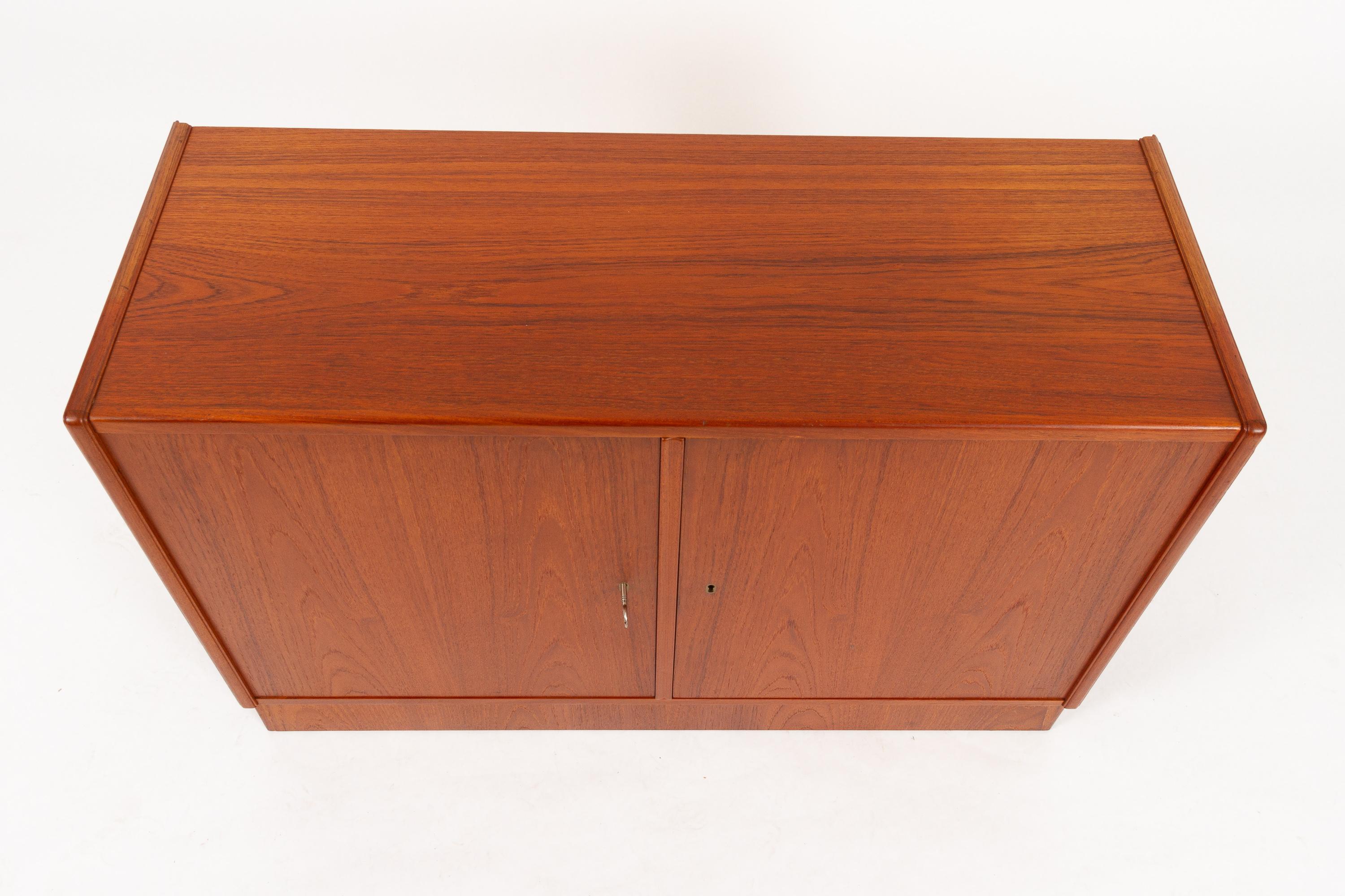 Vintage Danish Teak Cabinet 1960s.
Midcentury modern teak sideboard with two doors and two compartments. Each compartment is divided by one shelf. Shelves are adjustable by hand. Each door has a lock, and one key is included, fits both locks.