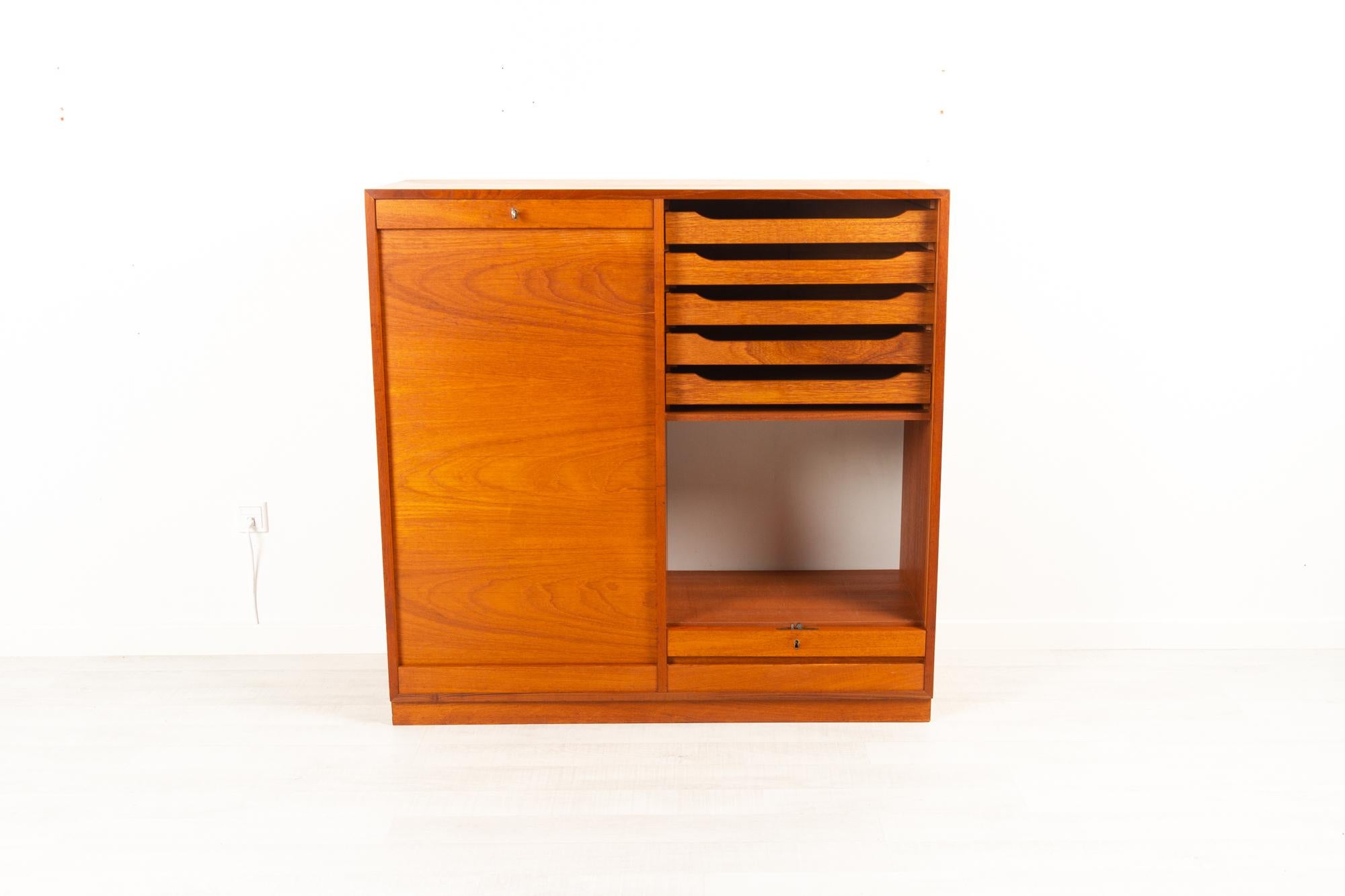 Vintage Danish teak cabinet with tambour front, 1960s
Danish modern large double filing cabinet with vertical sliding tambour doors in teak. Two separate compartments each with five drawers and open shelf. Drawers in solid wood with dovetail