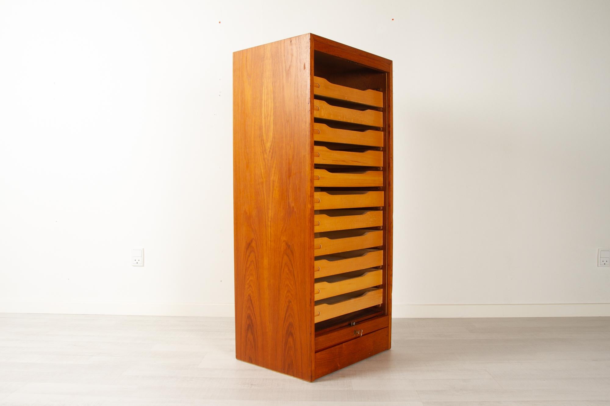 Vintage Danish teak cabinet with tambour front, 1960s
Danish modern filing cabinet with vertical sliding tambour door in teak. 11 wide drawers in solid beech. Rolling door opens with key. Key is included. The teak has a warm color and a vivid grain