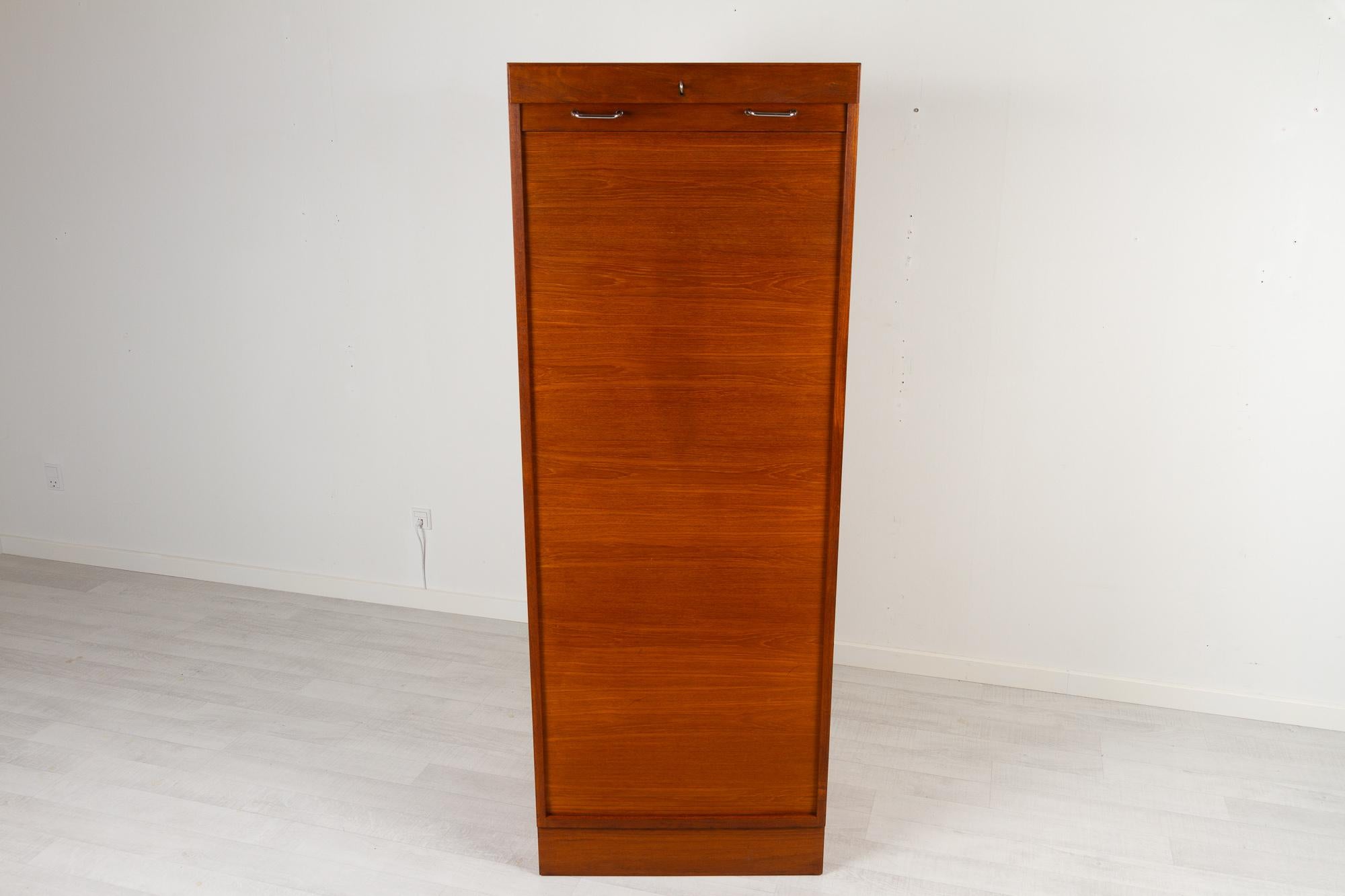Vintage Danish teak cabinet with tambour front, 1960s
Tall Danish modern filing cabinet with vertical sliding tambour door in teak. 3 wide drawers and 2 shelves. Both shelves and drawers can be placed as desired. Rolling door opens with key. Key is