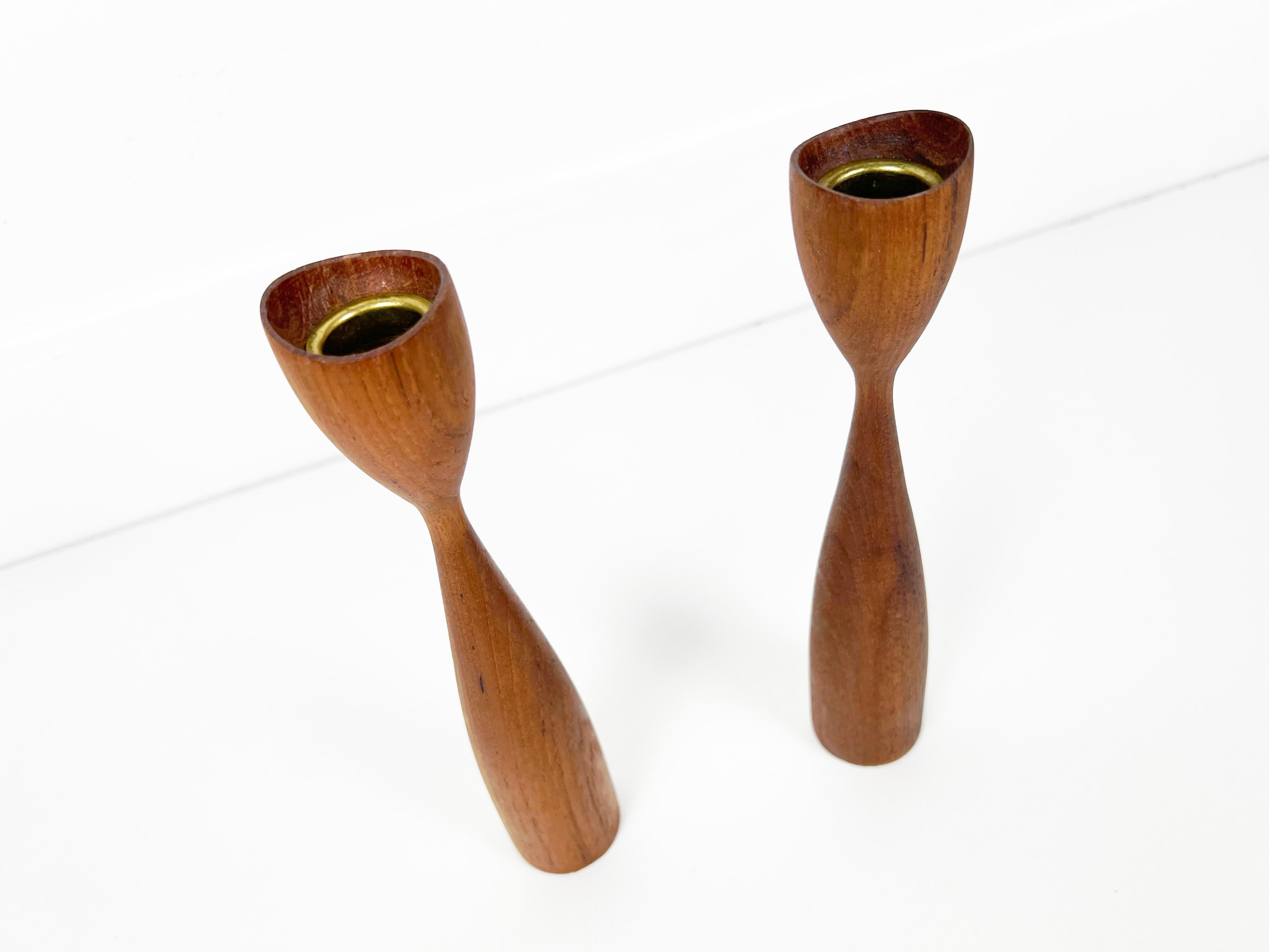 Pair of vintage Scandinavian sculptural candleholders with asymmetric tops. Lathe turned from solid teak with brass candle holder inserts. 

Origin: Denmark

Year: 1960s

Style: Mid Century Modern / Danish Modern / Scandinavian

Dimensions: