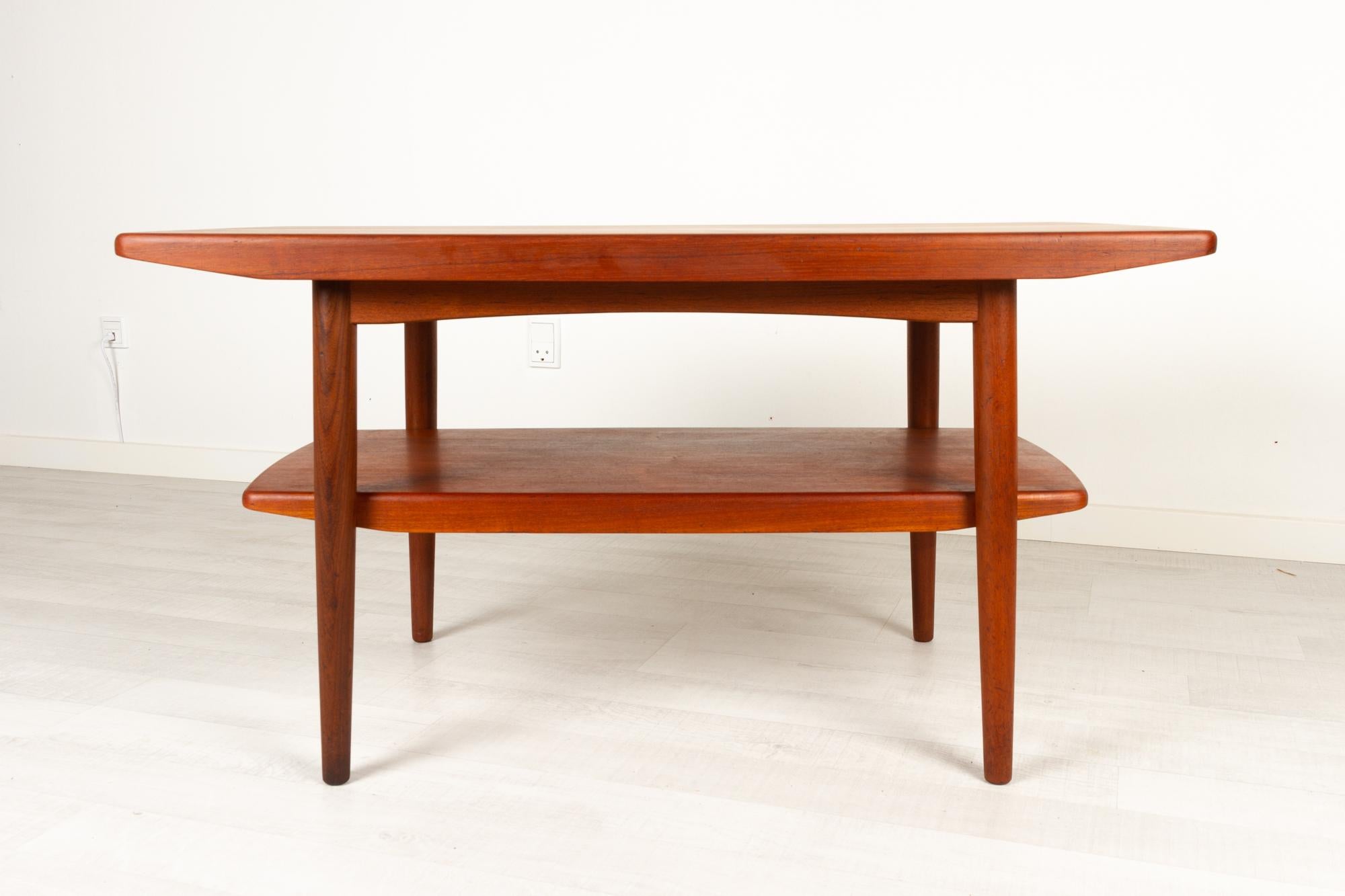 Vintage Danish teak coffee table with shelf 1960s
Danish Mid-Century Modern compact and elegant coffee table with underlying magazine shelf. Very good build quality and craftsmanship. Round tapered legs in solid teak. Table top and shelf edged with