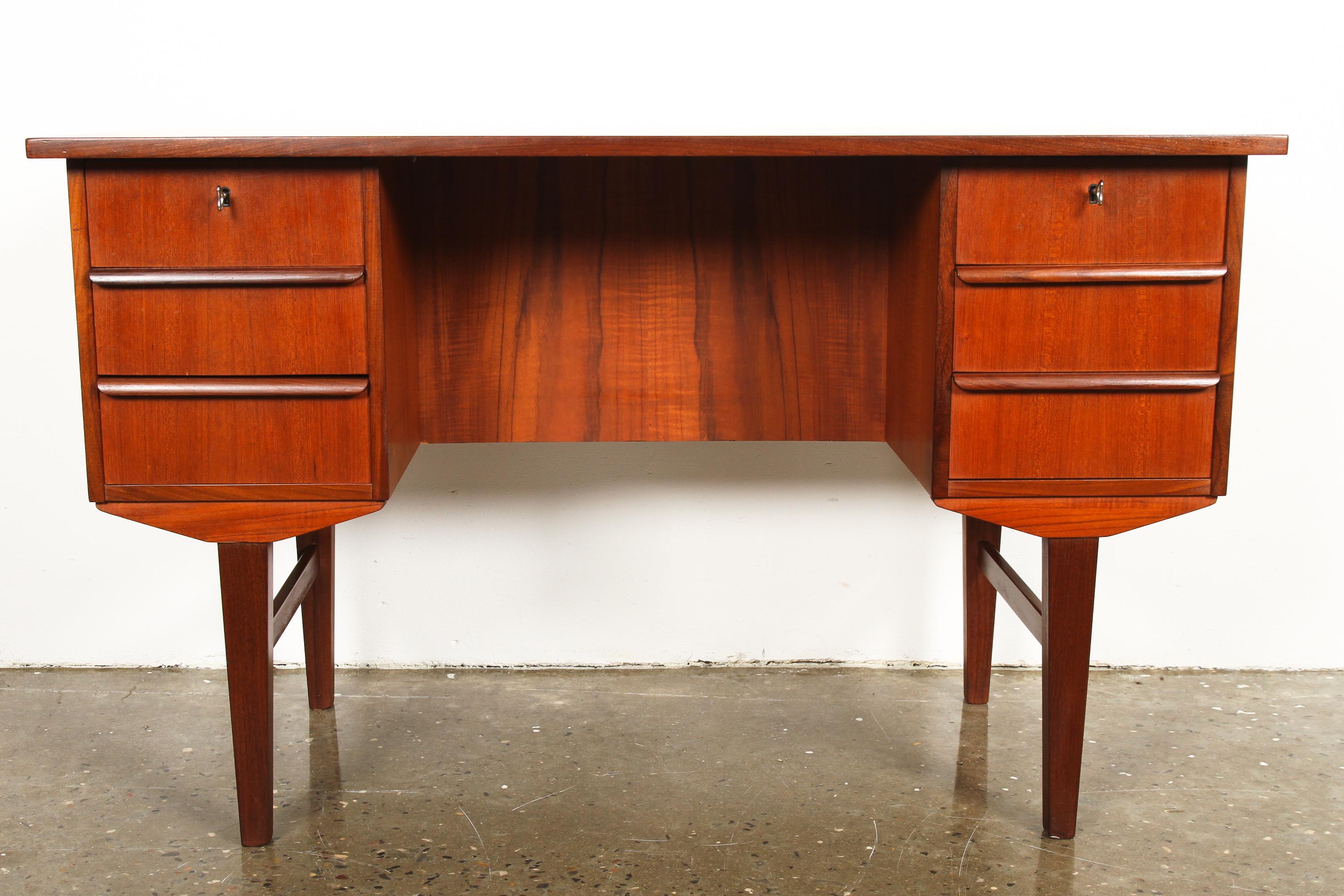 Lovely Danish Mid-Century Modern freestanding teak writing desk. If features six drawers in front, and two book shelves on the back. Two top drawers comes with a key each. Tabletop has been refinished, and treated with teak oil and wax for extra