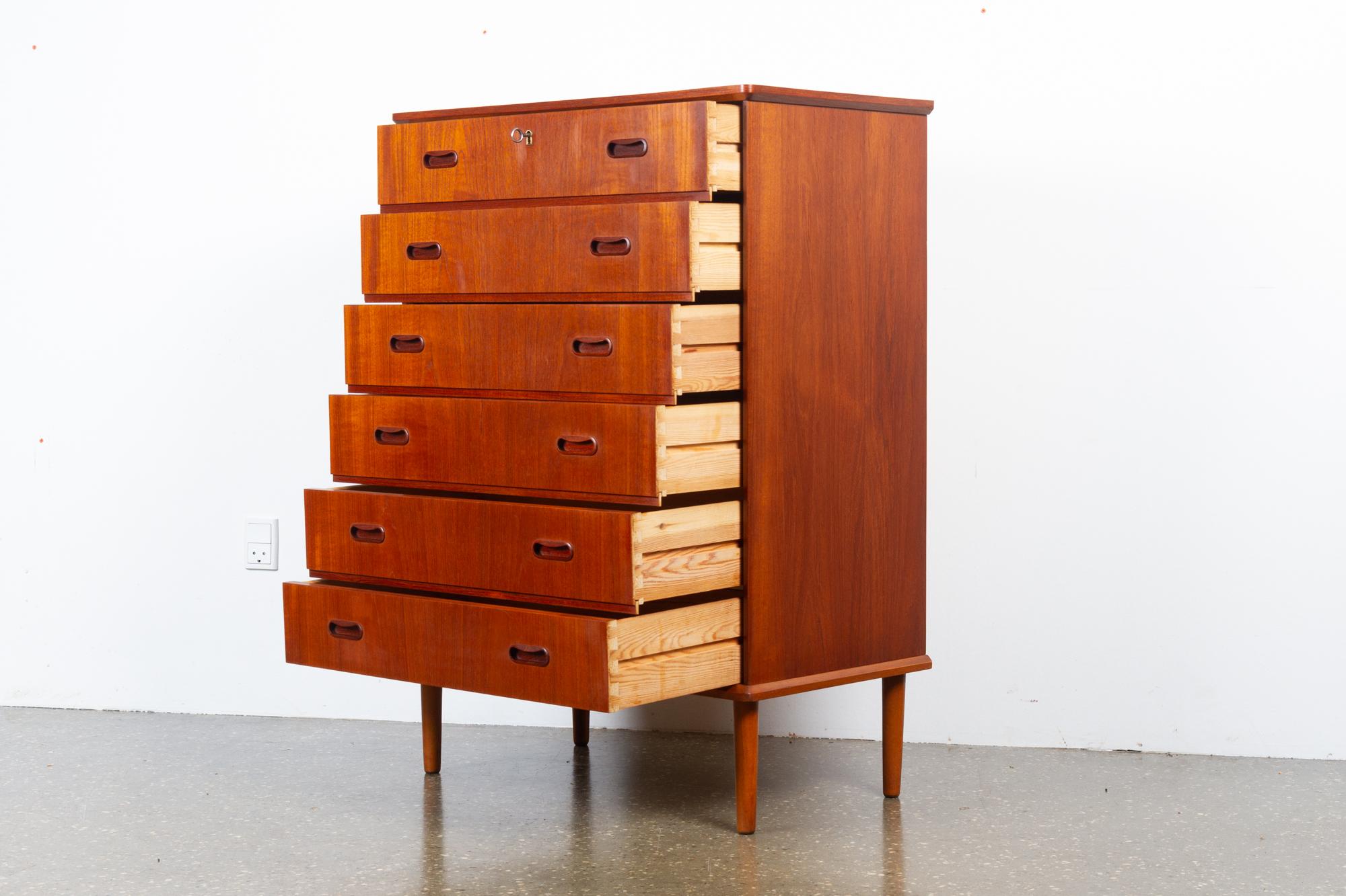 Vintage Danish teak dresser with 6 drawers, 1960s
Elegant Danish modern chest of drawers in beautiful teak veneer with oak frame and round tapered legs. Six large drawers with sculpted pulls in solid teak. Top drawers has a lock and key. Varm and