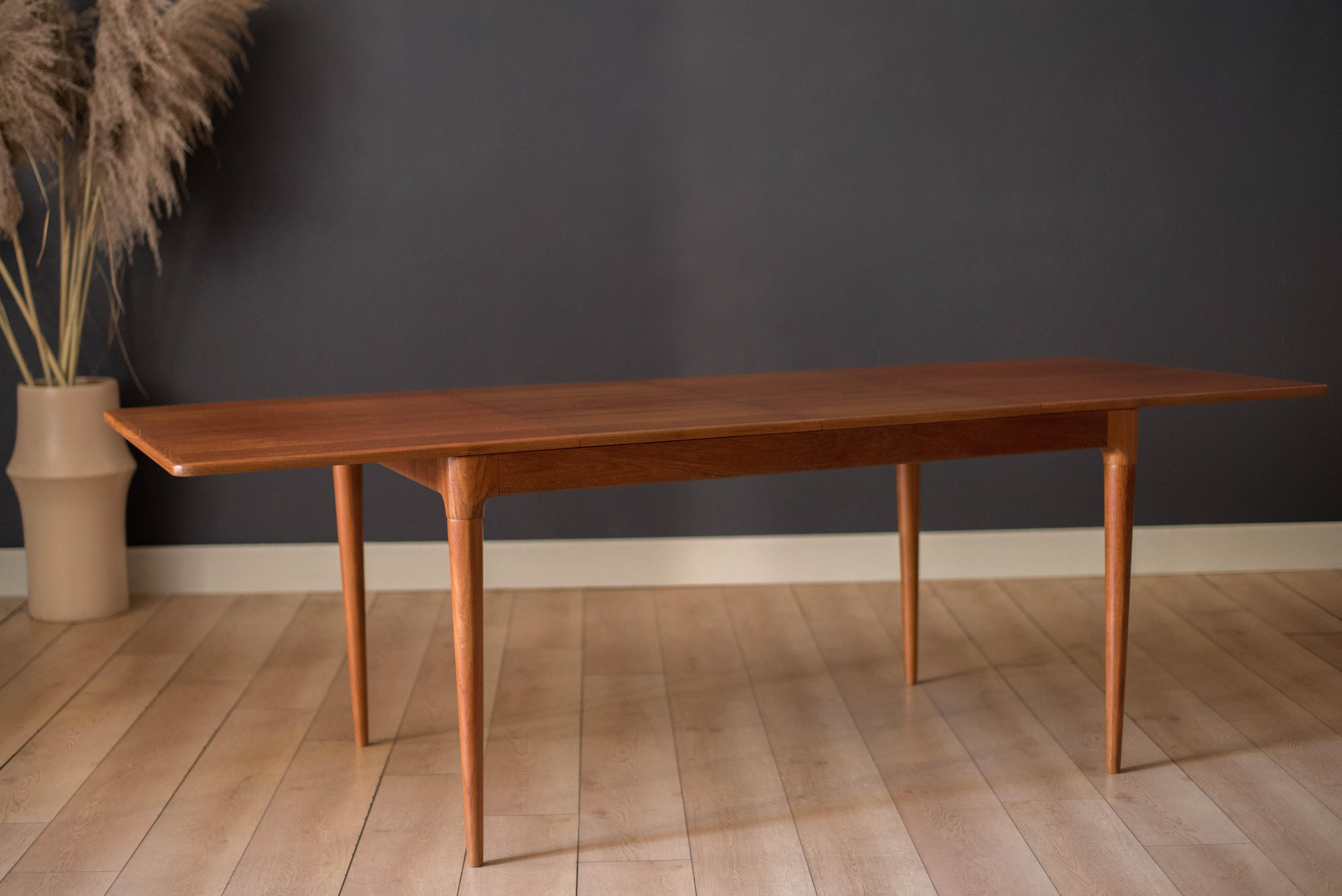 Mid century modern expandable dining table in teak designed by Arne Hovmand-Olsen for Mogens Kold, Denmark. This versatile piece displays continuous wood grains and rounded edge banding supported by sculptural tapered legs. Includes two butterfly