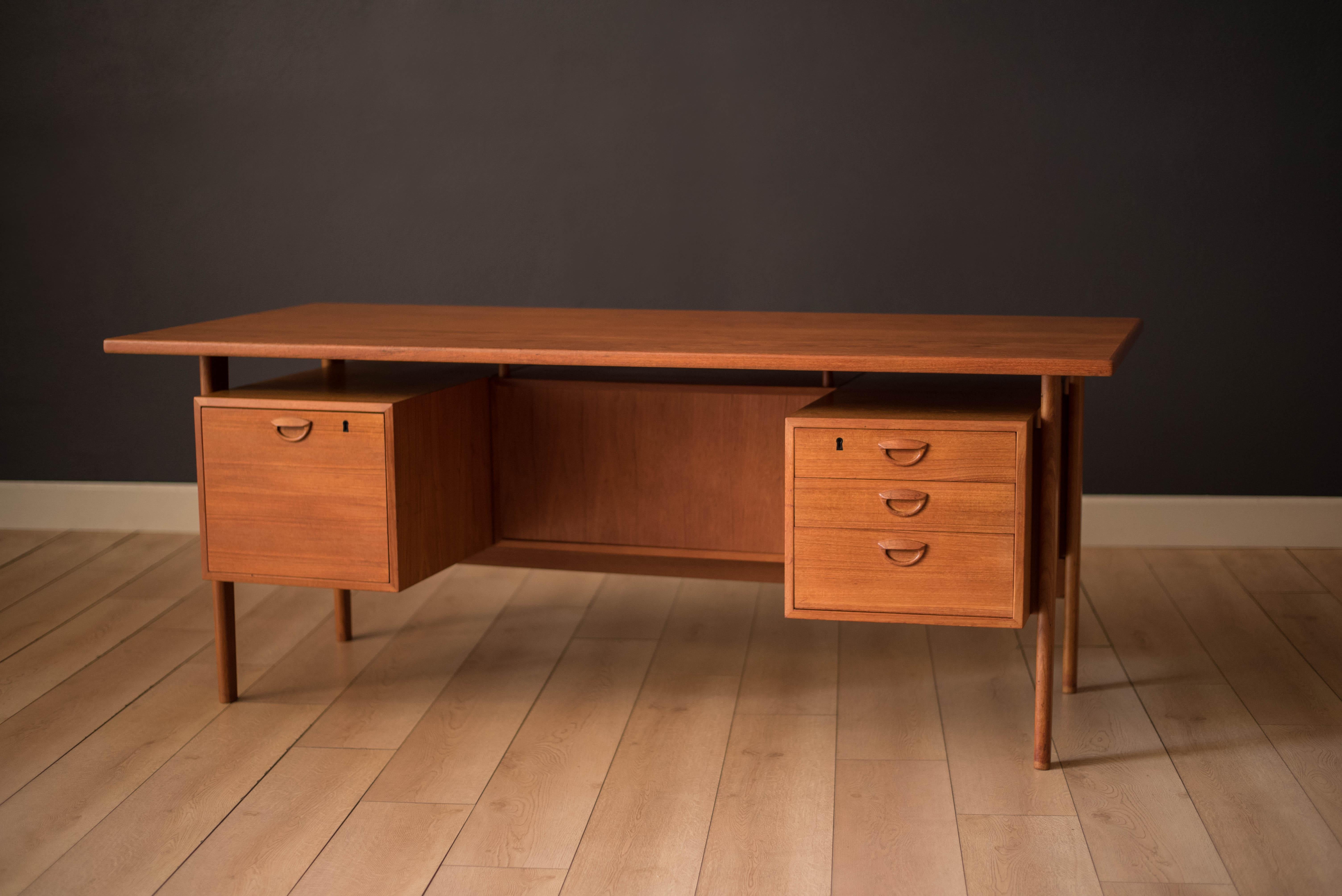 Mid century executive desk designed by Kai Kristiansen in teak. Offers a desktop with plenty of work surface space equipped with three dovetailed drawers and a locking filing cabinet with signature sculpted handles. This unique piece can be