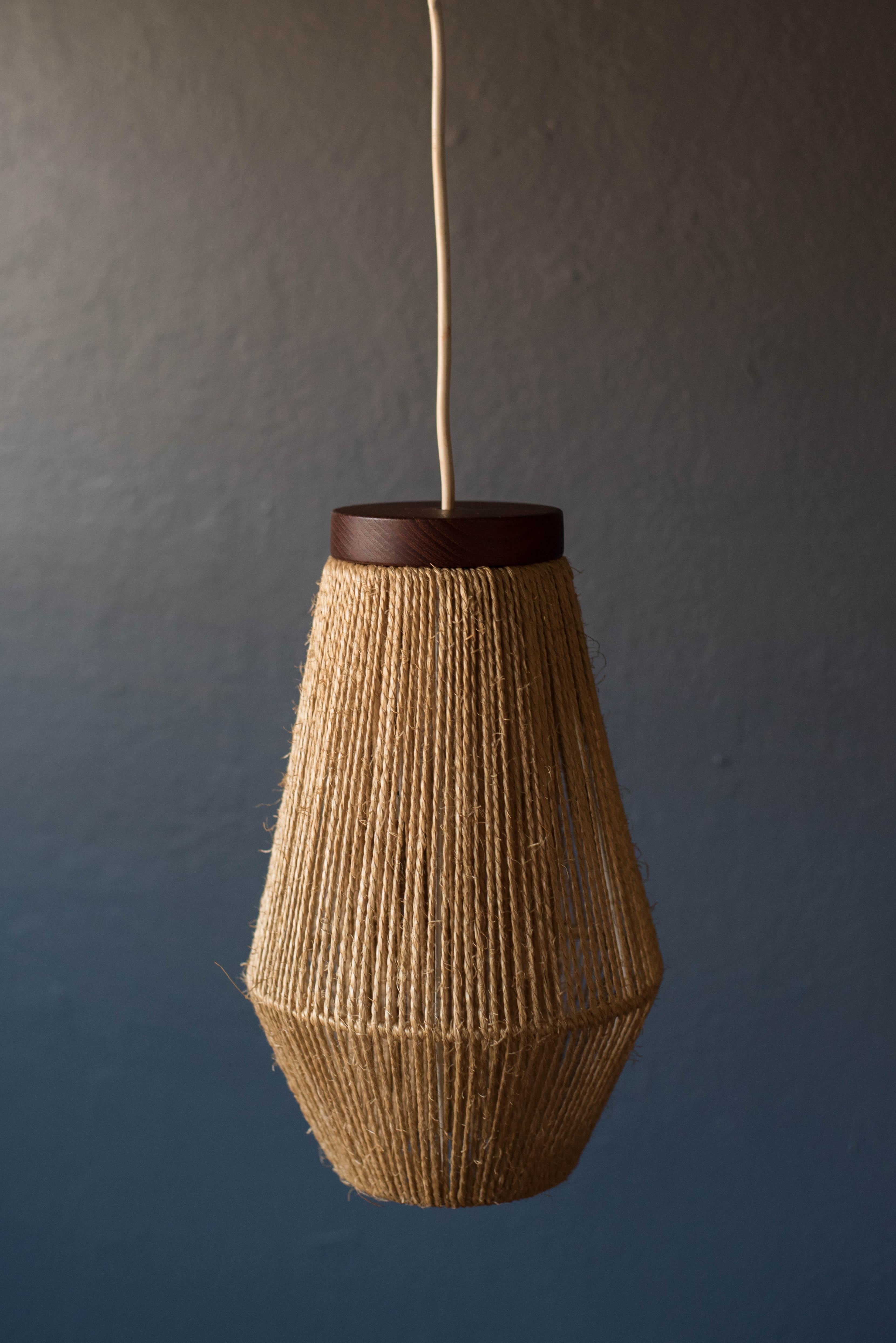 Mid-Century Modern hanging pendant light designed by Ib Fabiansen for Fog and Morup, circa 1960s. This piece displays a unique symmetrical shape wrapped in natural sisal fibers accented in teak.




Offered by Mid Century Maddist