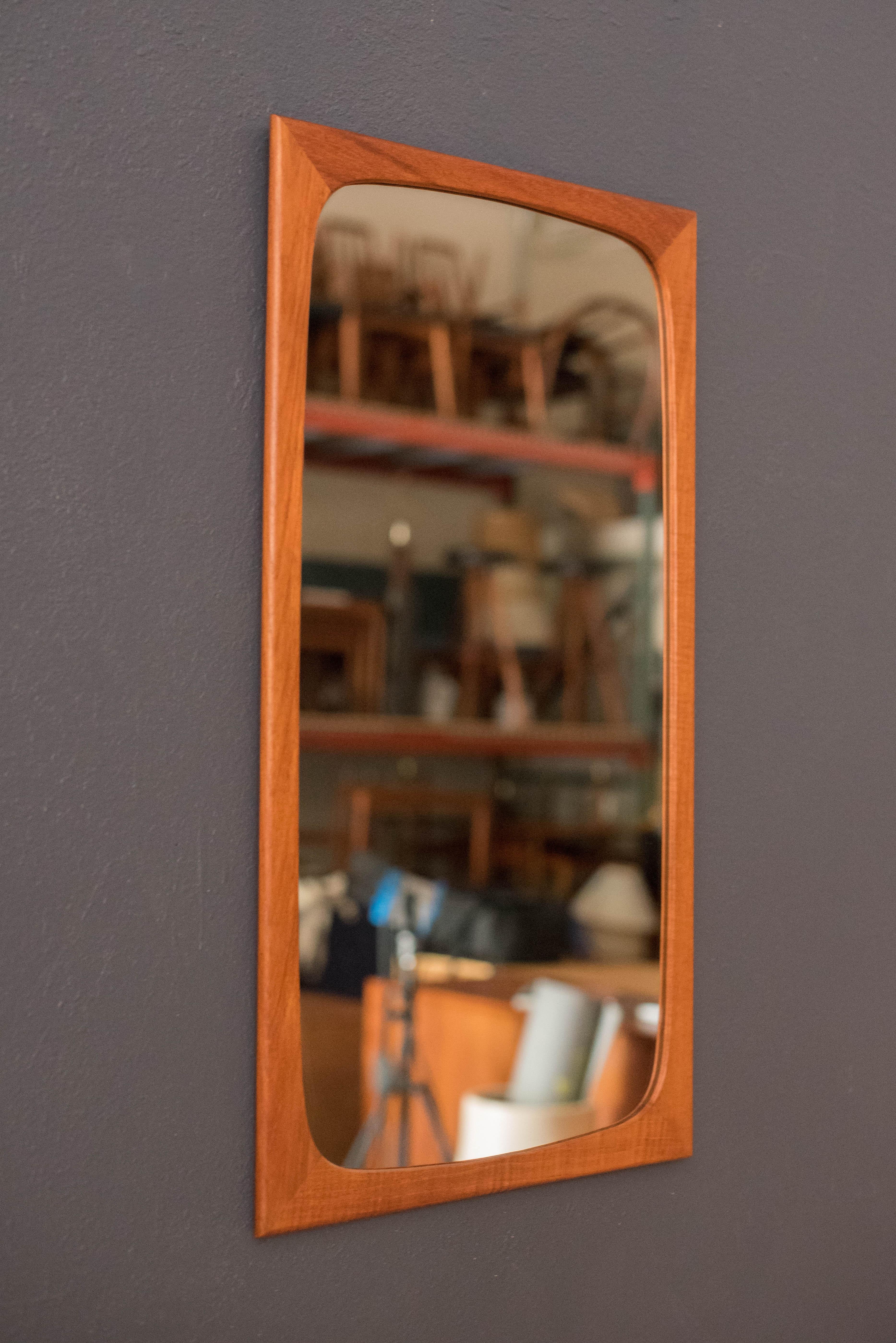 Mid-Century Modern wall mirror by Aarhus Glasimport og Glassliberi, Denmark. This decorative mirror has a contoured rectangular teak frame that fits perfectly in an entryway space or as an accent vanity piece.