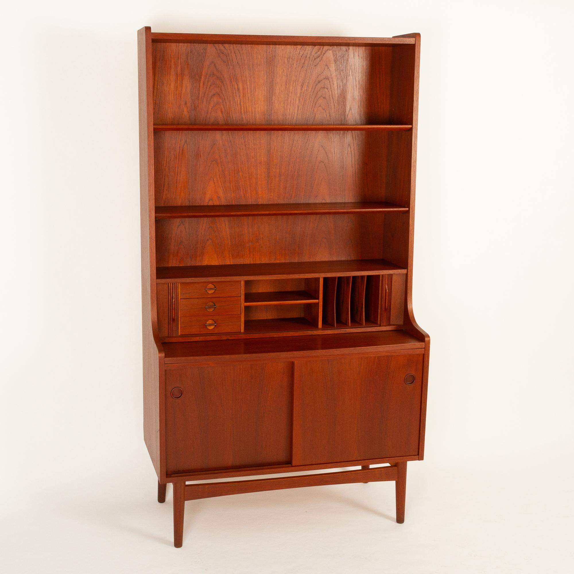 Vintage Danish teak high Secretaire by Johannes Sorth for Bornholms Møbelfabrik, 1960s. Made on the small island of Bornholm.
Tall Mid-Century Modern secretary with draw out tabletop and tambour doors. Desk area with three small drawers, a shelf