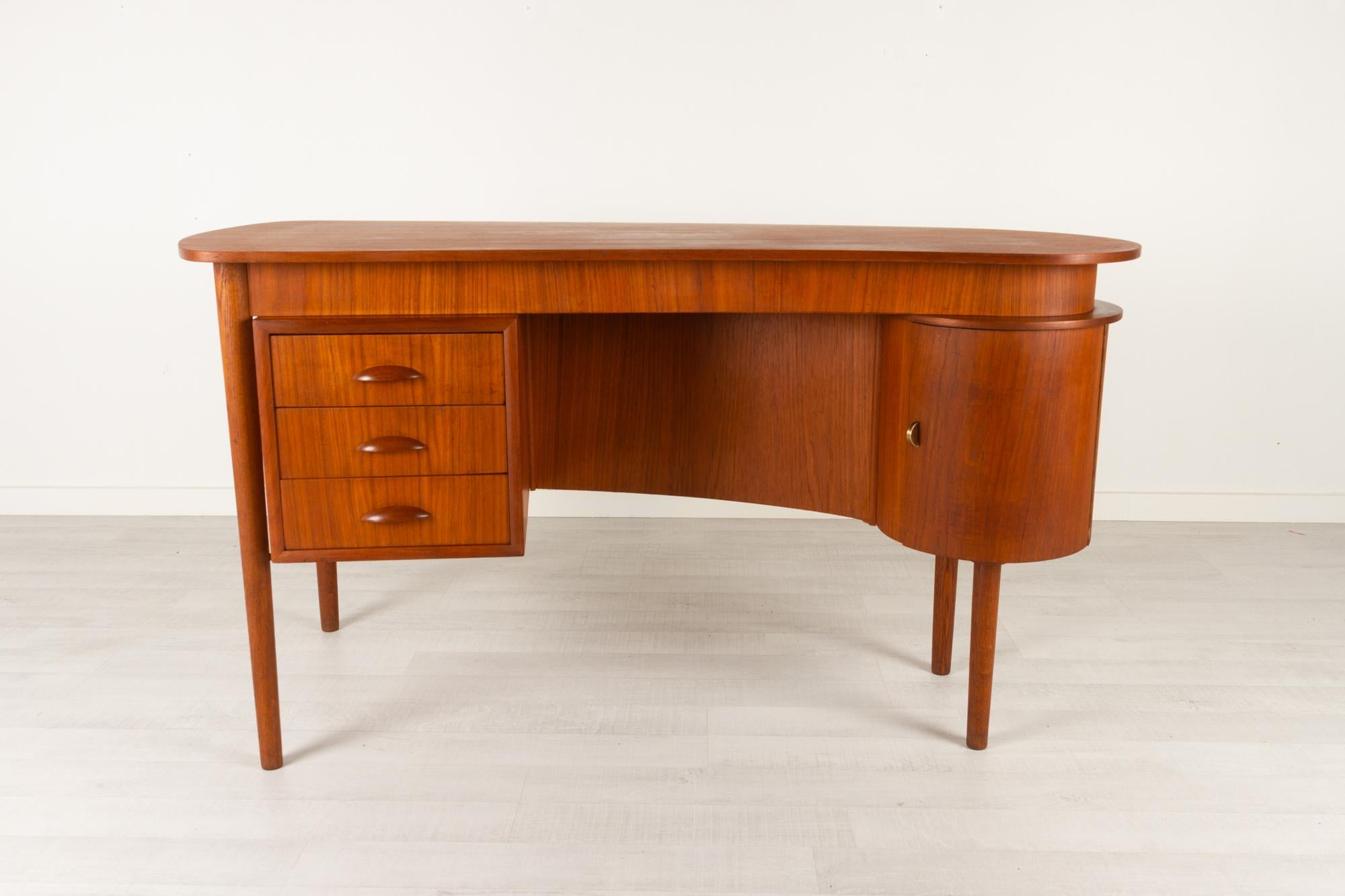 Vintage Danish teak kidney desk, 1950s
Danish Mid-Century Modern freestanding organically shaped writing desk. Kidney shaped table top in teak veneer. Drawer section with three drawers with sculpted pulls in solid teak. Round corner cabinet with