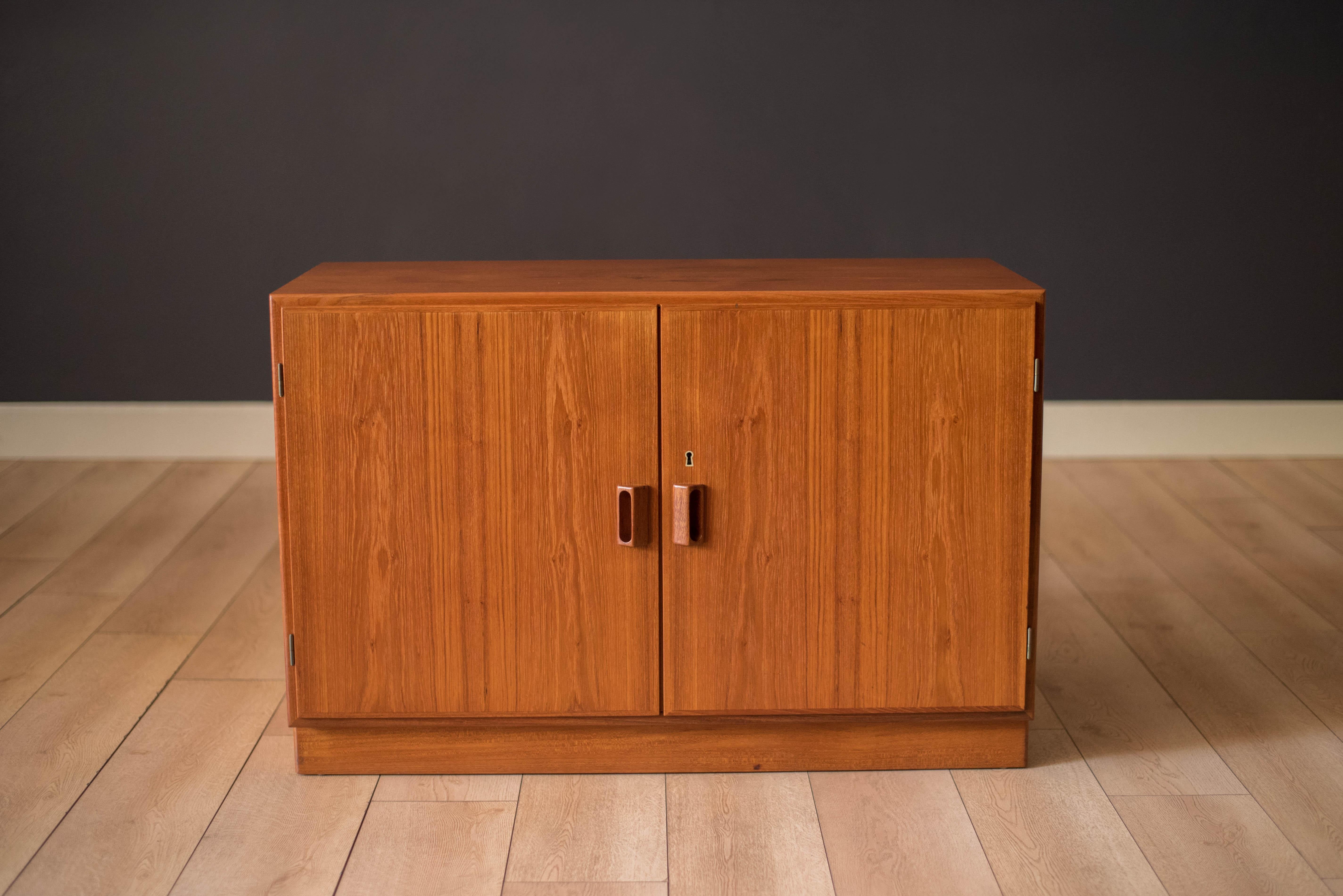 Mid-Century Modern buffet sideboard cabinet in teak designed by Borge Mogensen circa 1960's. This unique piece is accented with signature sculpted handles and brass hardware providing outswing doors and open storage space. Includes one adjustable