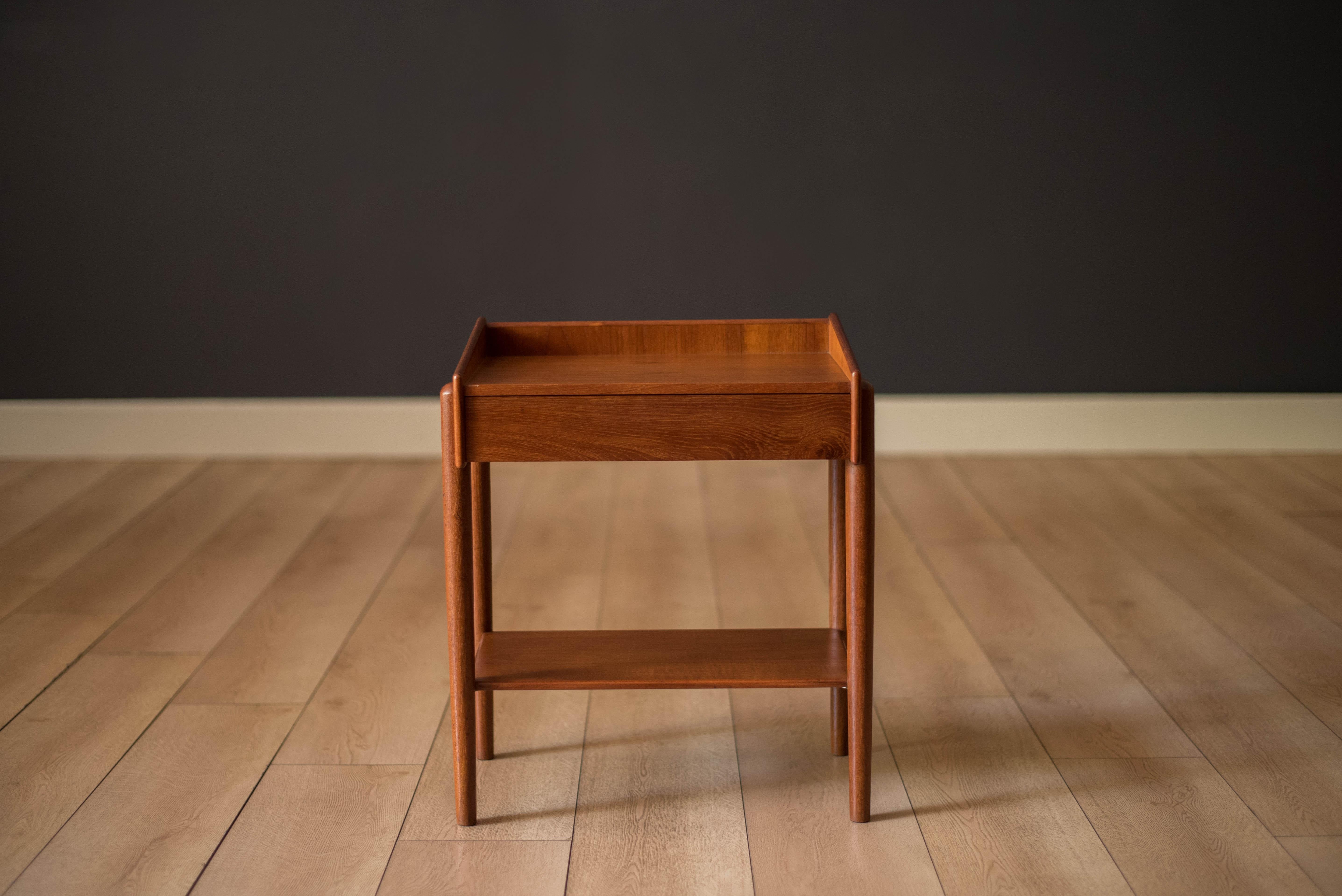Mid-Century Modern bedside table nightstand designed by Borge Mogensen for Soborg Mobler, circa 1950s. This unique piece is made of old growth teak and features one dovetail drawer and a lower tier shelf for extra storage. Complete with a finished