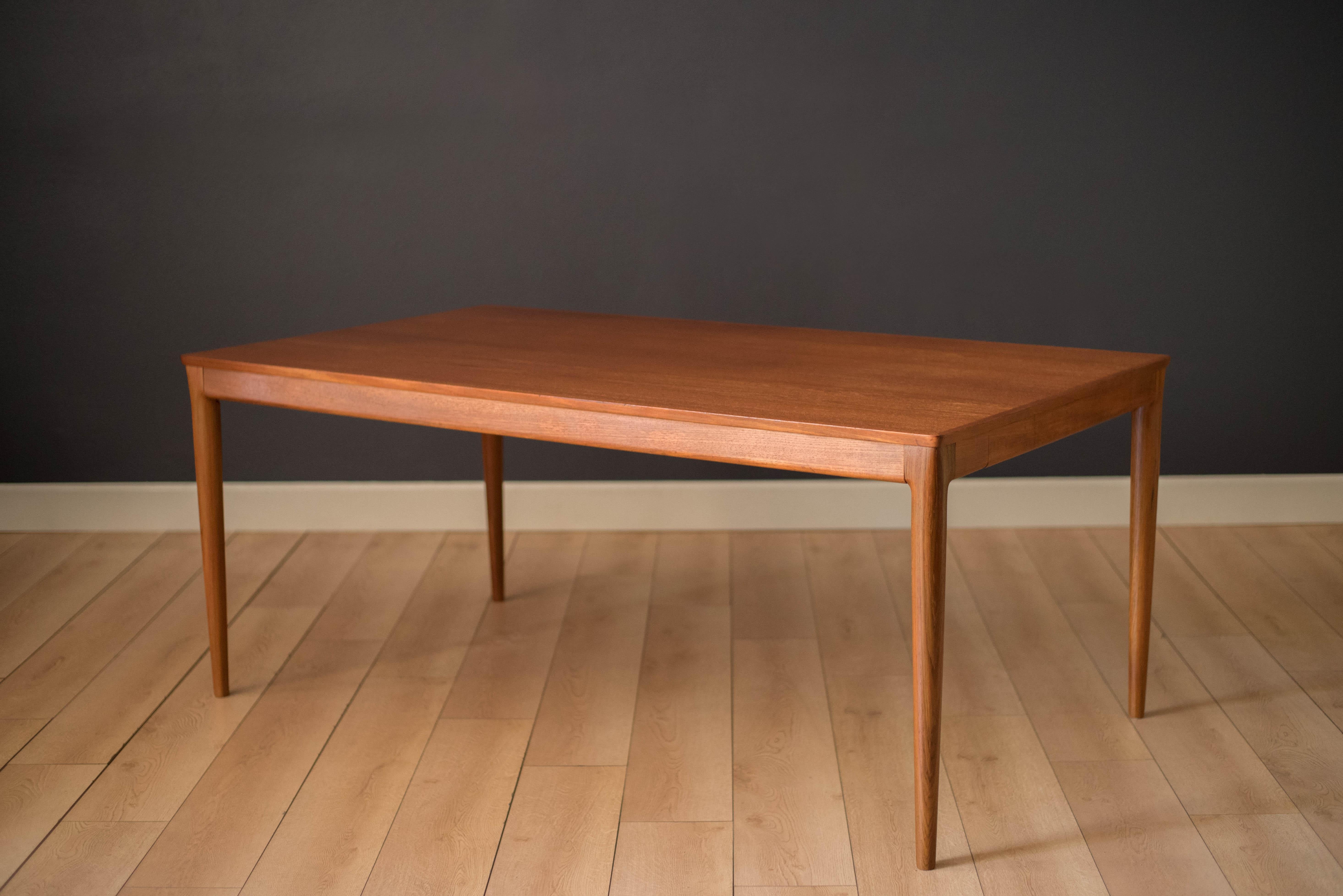 Mid-Century Modern expandable dining table in teak, circa 1960s. This unique piece features a seamless design including two leaves that cleverly store in hidden pullout drawers underneath the table, easy enough for one person to set up. Supported by