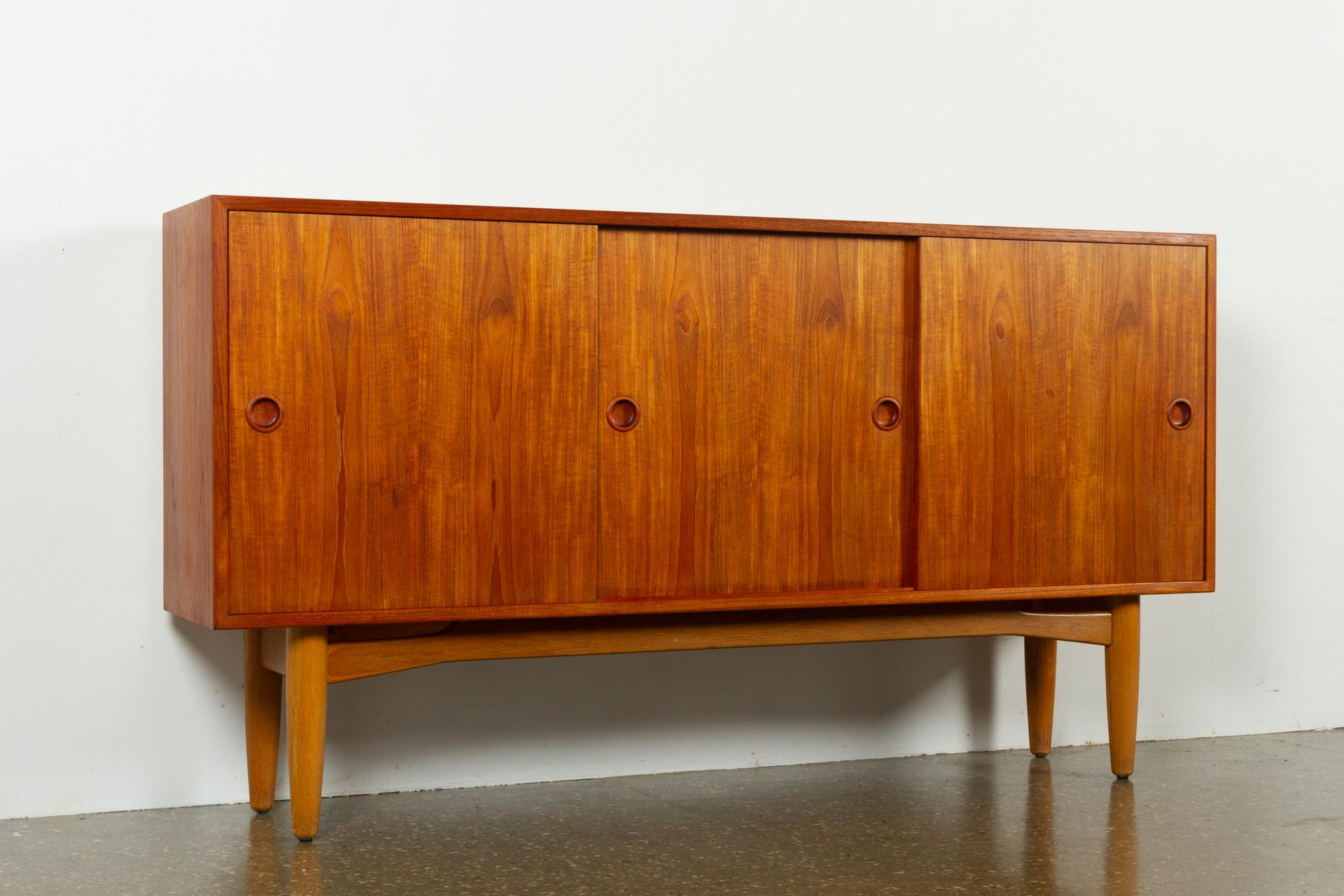 Vintage Danish teak sideboard, 1960s
Mid-Century Modern Danish lowboard with three sliding doors. Round embedded grips in solid teak. Behind doors are two compartments, one narrow and one wide, each with two height adjustable shelves. 
Inside of