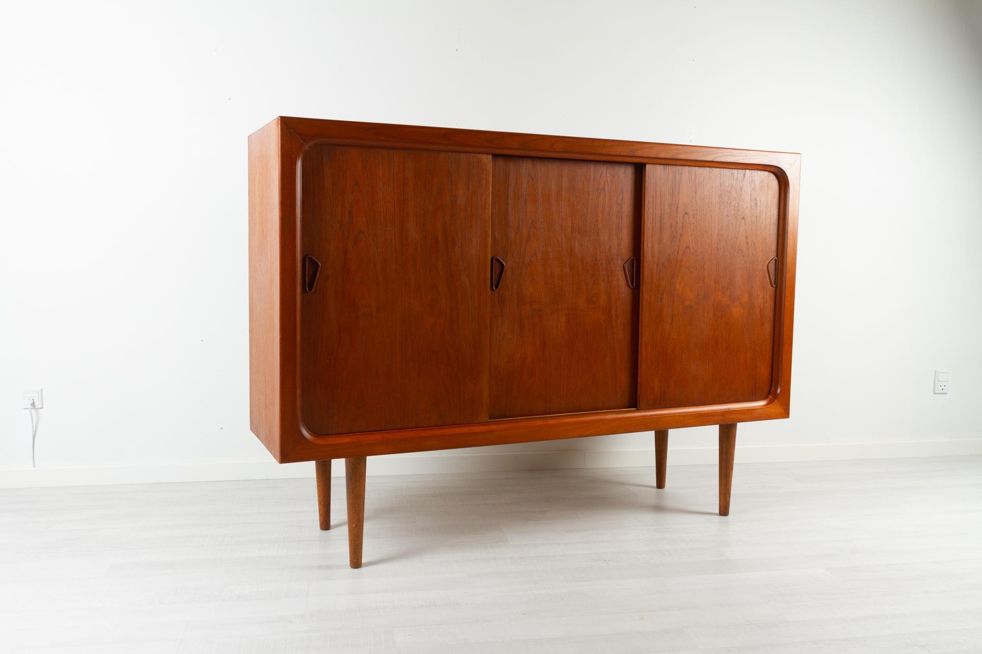 Vintage Danish teak sideboard 1960s
Mid-century modern highboard in teak with three sliding doors made in Denmark in the 1960s. Very spacious large cabinet with two height adjustable shelves. Triangular door handles in solid teak. Also features a