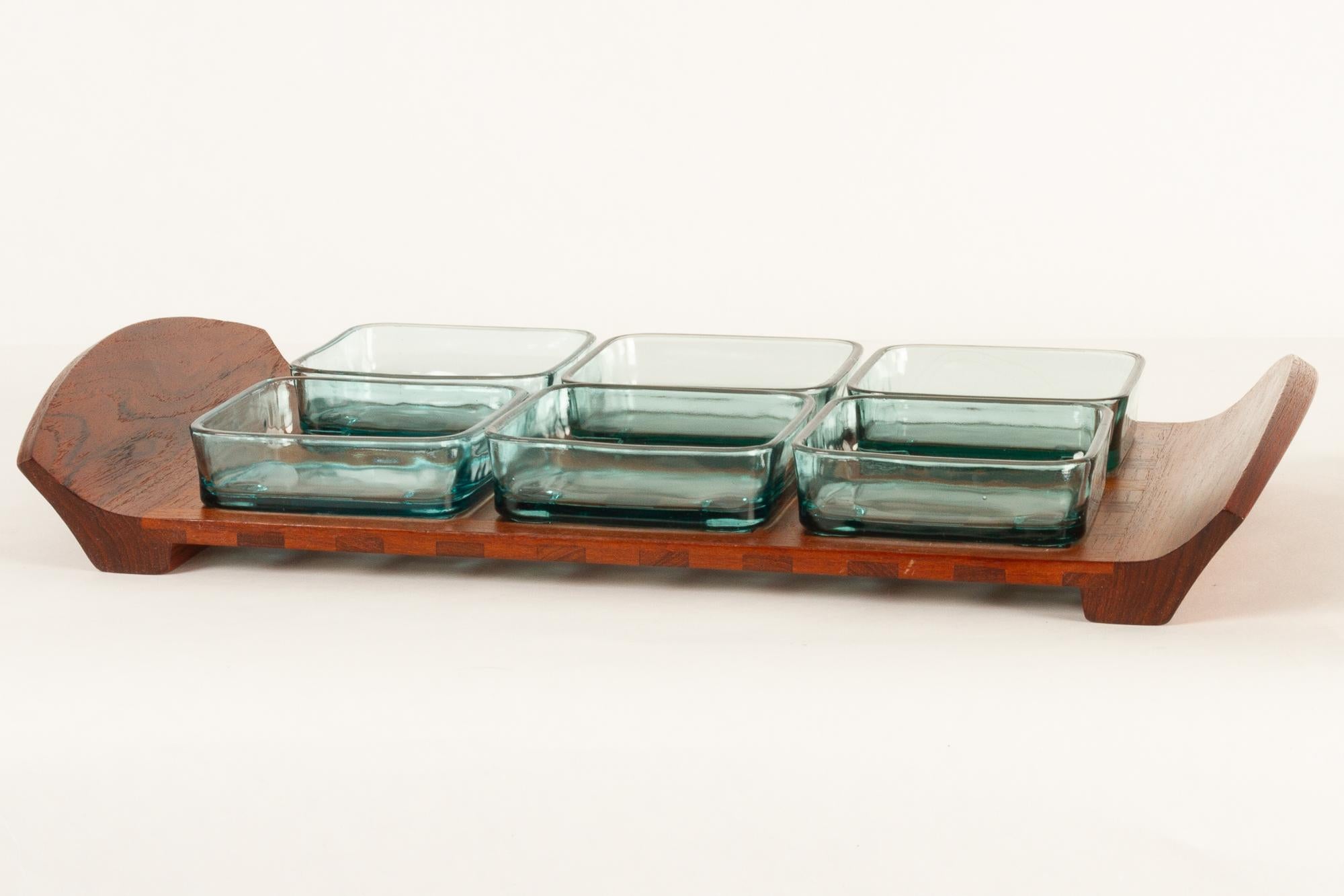 Vintage Danish teak tray with glass bowls by Jens Harald Quistgaard for IHQ Dansk Designs, 1960s.
Serving tray in solid teak with six green glass dishes. Each dish has feet that fits into the lattice on the tray. Measures: Length 46 cm. Marked JHQ