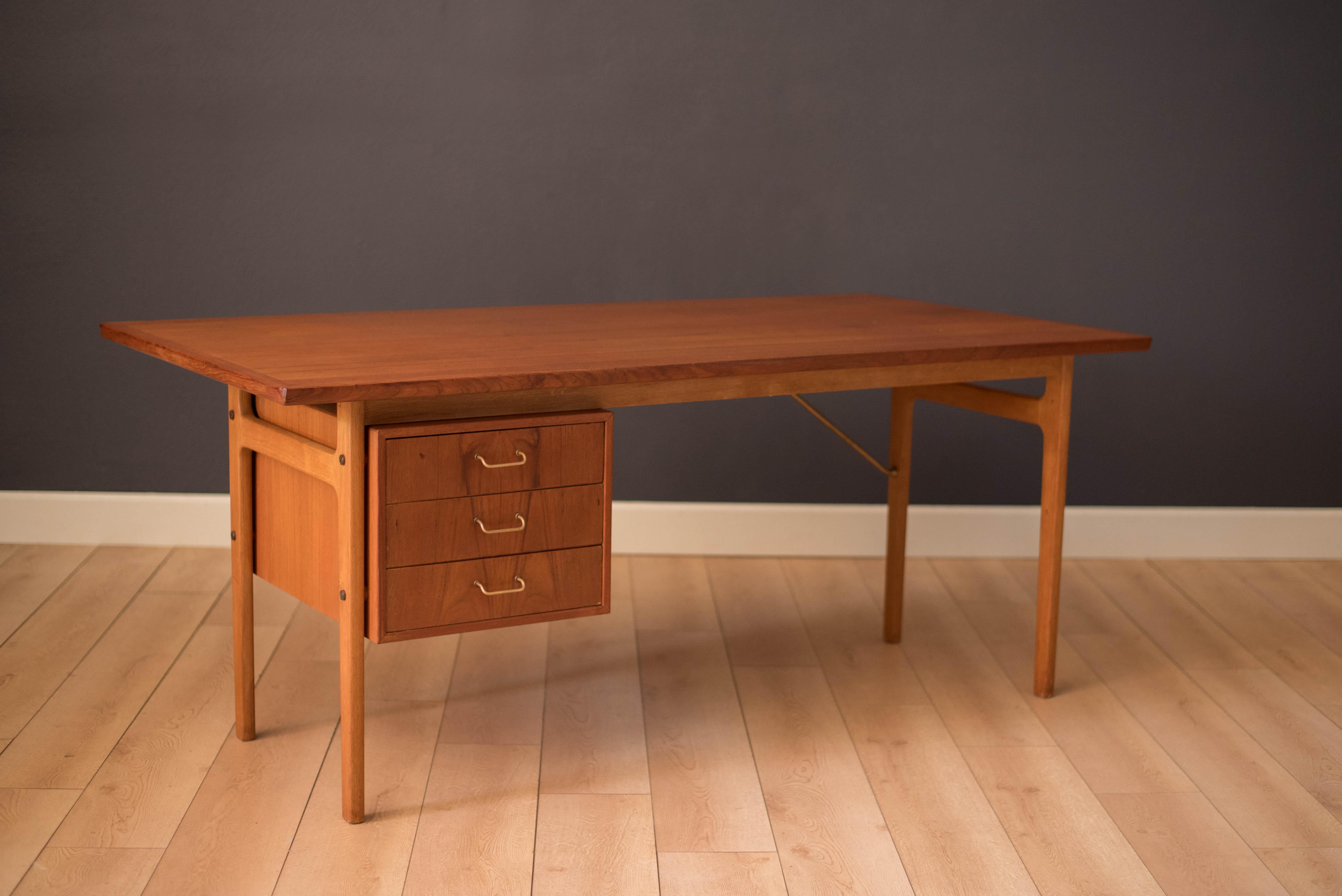 Mid century writing desk designed by Torben Strandgaard for Falster Mobelfabrik. This piece features a large teak desktop equipped with three dovetailed drawers and brass accents. Supporting leg base is made of oak.