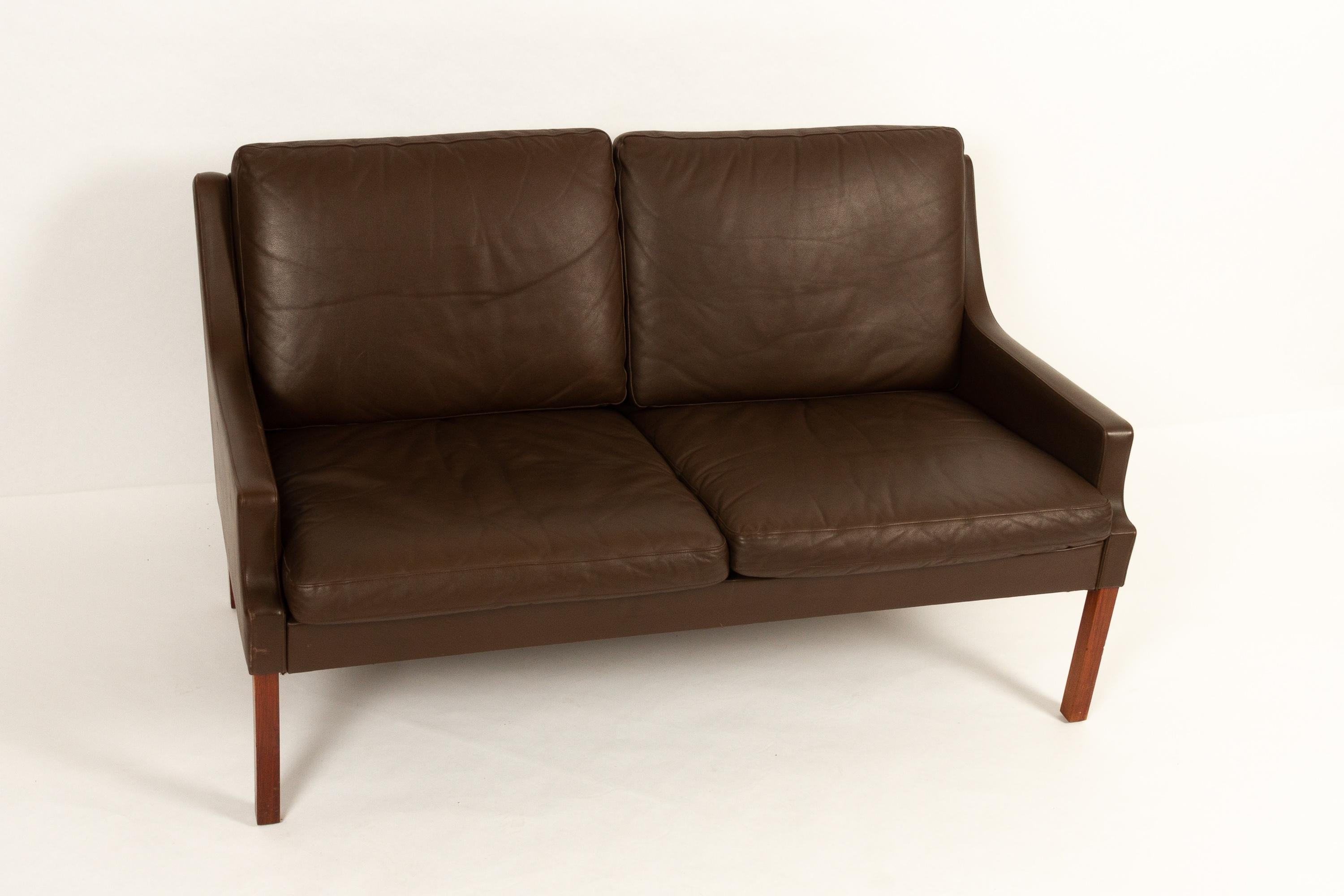 Vintage Danish two-seat leather sofa by Georg Thams for Vejen Møbelfabrik 1970s.
Elegant Classic Mid-Century Modern two-seater sofa in dark chocolate colored leather, standing four square hardwood legs. Soft and very comfortable down filled