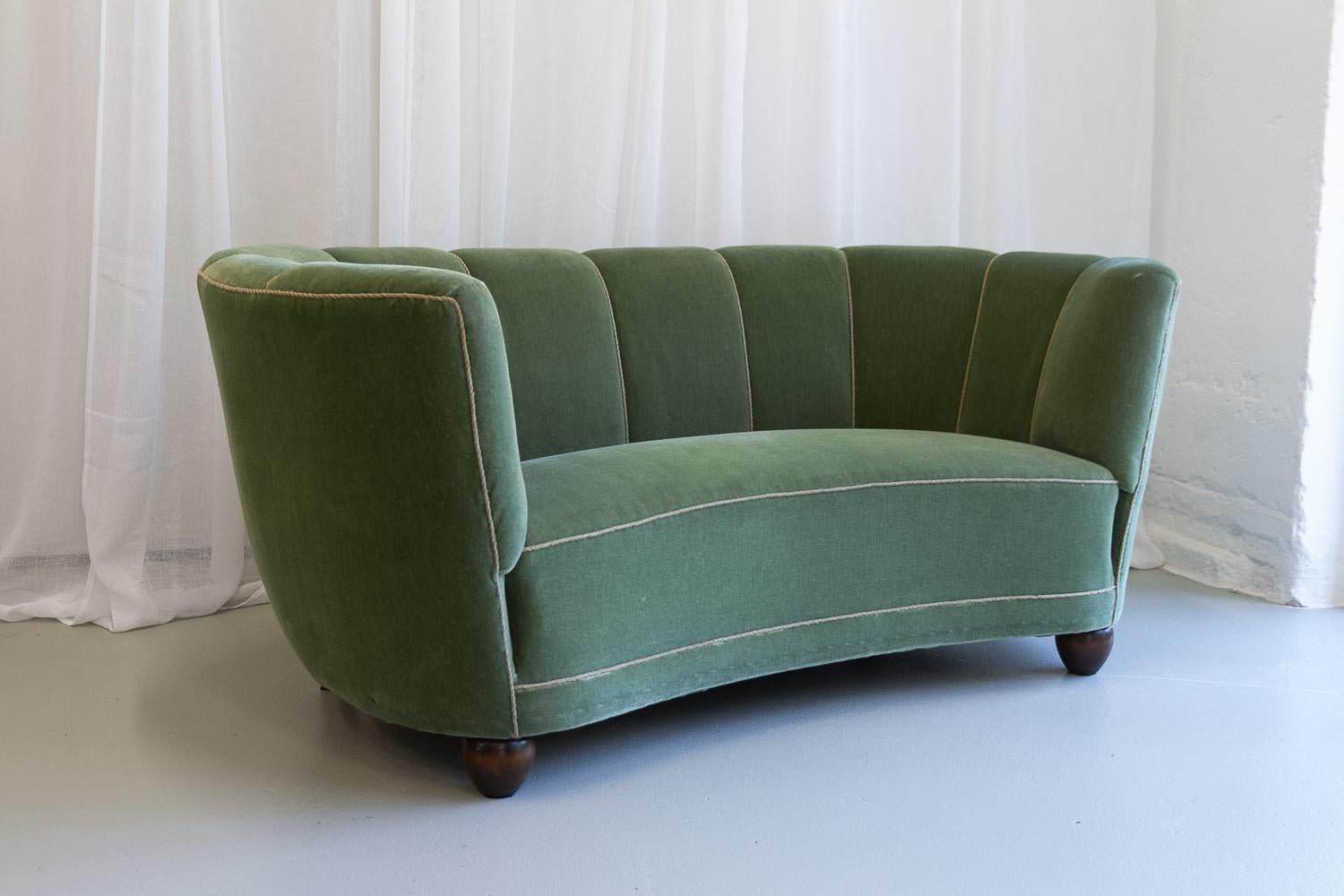 Vintage Danish velvet Art Deco banana sofa, 1940s.

Vintage Art Deco banana-shaped loveseat upholstered in light green mohair velvet made by cabinetmaker in Denmark in the 1940s. Curved two-seater with original spring and velour upholstery. Feet in