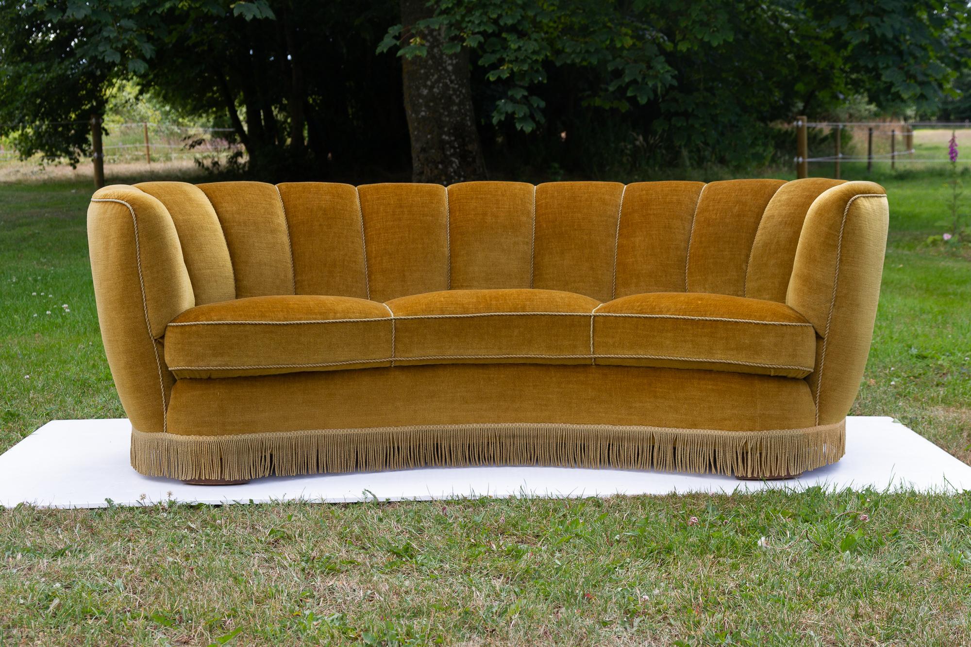 Vintage Danish velvet banana sofa, 1940s
Vintage Art Deco banana-shaped sofa upholstered in green/yellow/golden velvet made by Danish cabinetmaker in the 1940s. Curved three-seater with original spring and velour upholstery, base edged with