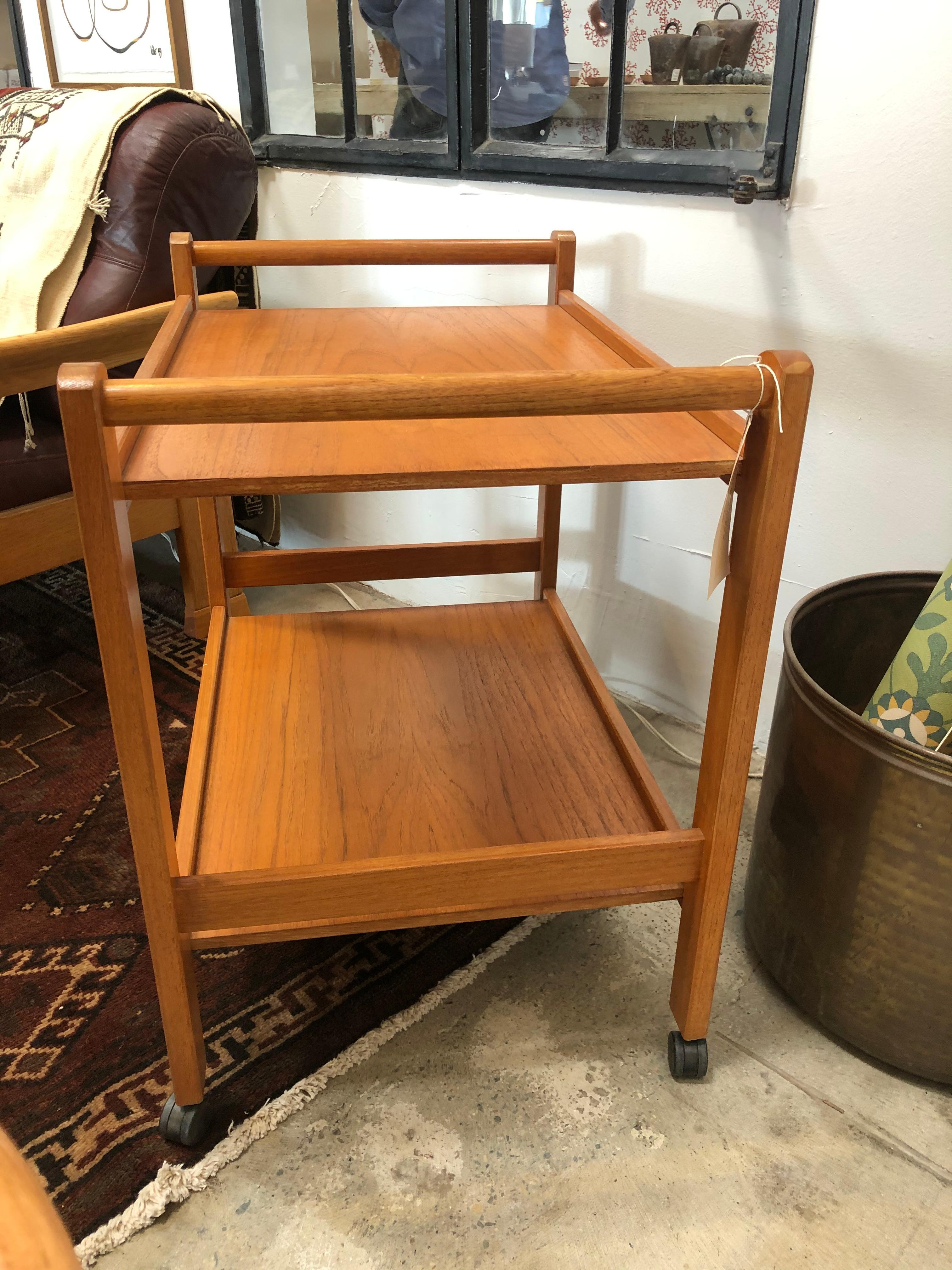 This Danish bar cart has four small wheels in good condition making it a mobile serving cart. It is in excellent vintage condition and is sturdy enough to serve drinks or use as a plant stand. It features two long handles, one on each side, for ease