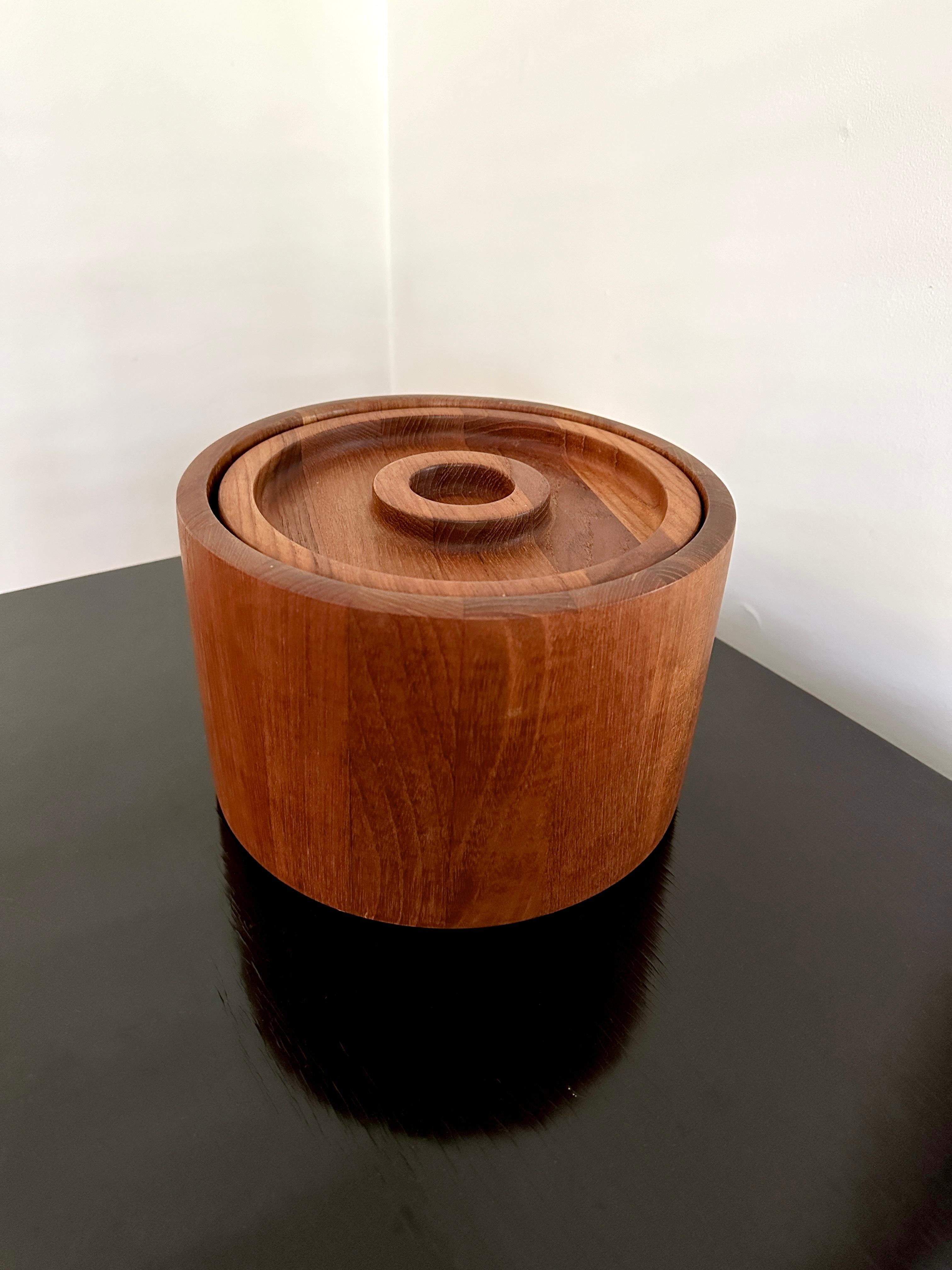 Un secchiello per il ghiaccio vintage in teak massiccio disegnato da Jens Quistgaard per Dansk. Il secchio ha un rivestimento in plastica nera. Il secchiello per il ghiaccio misura circa 6 1/4 pollici di altezza e 9 1/2 pollici di diametro. Il