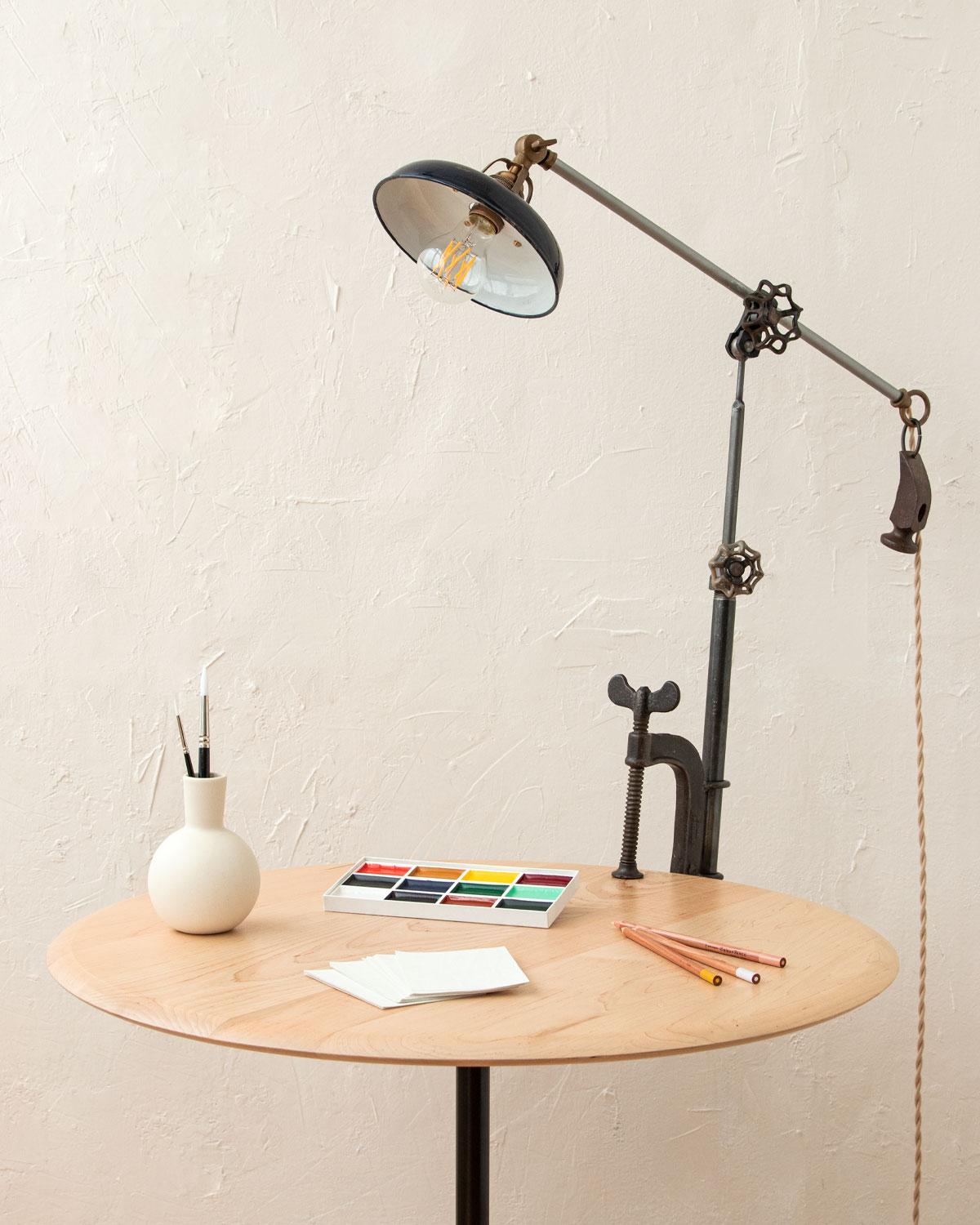 Robert True Ogden's one-of-a-like found object lamps are made by hand in Philadelphia. Crafted from pieces and parts sourced locally and abroad, no two lamps are alike. 

This clamp lamp has a vintage metal shade and a hammer-head counter-balance