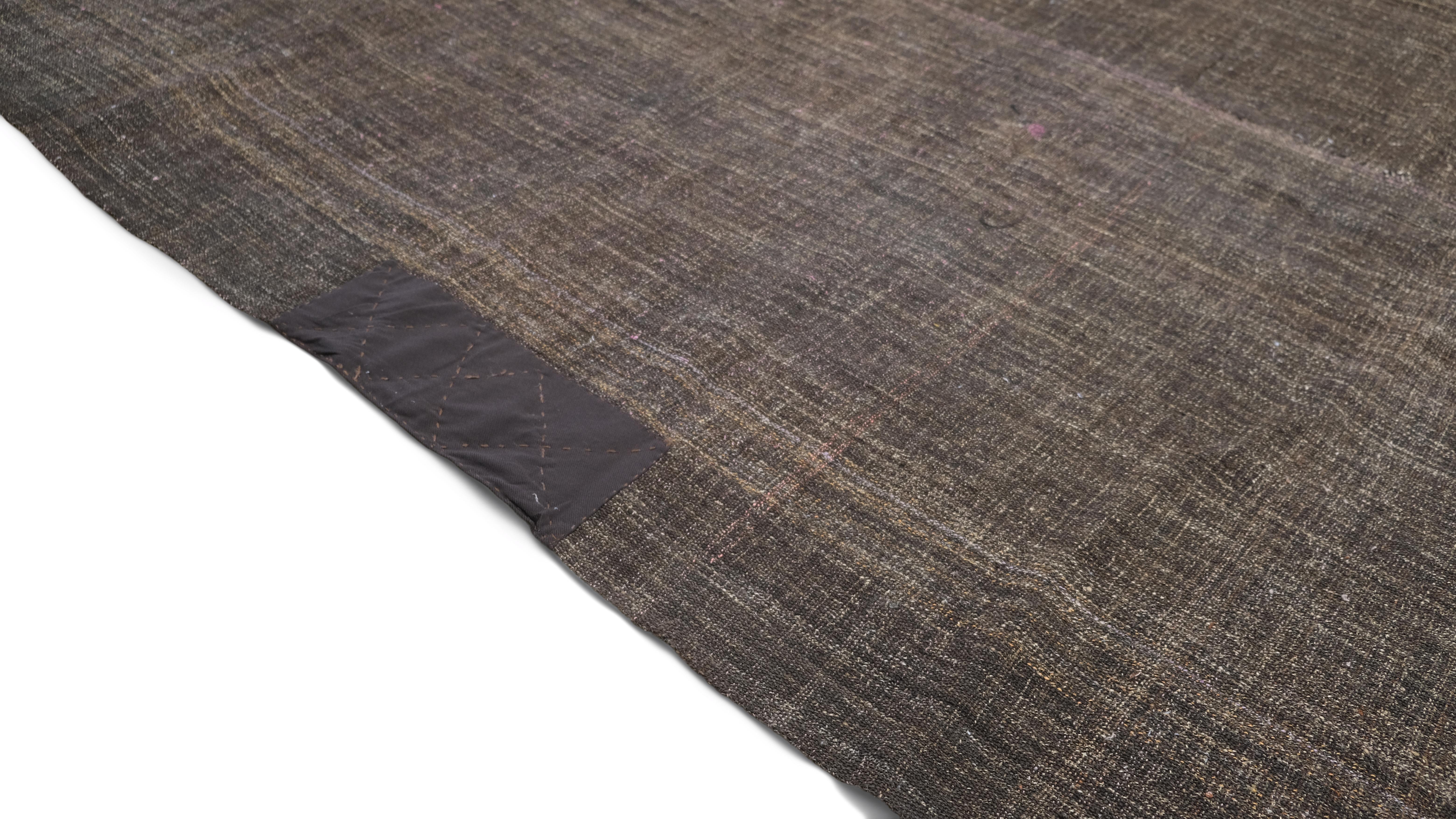 This hand-woven goat hair kilim is a rare and authentic vintage textile crafted by nomadic artisan. The rug features a subtle striated texture, achieved through the weaving of natural, undyed goat hair, creating an earthy brown tone. This minimalist