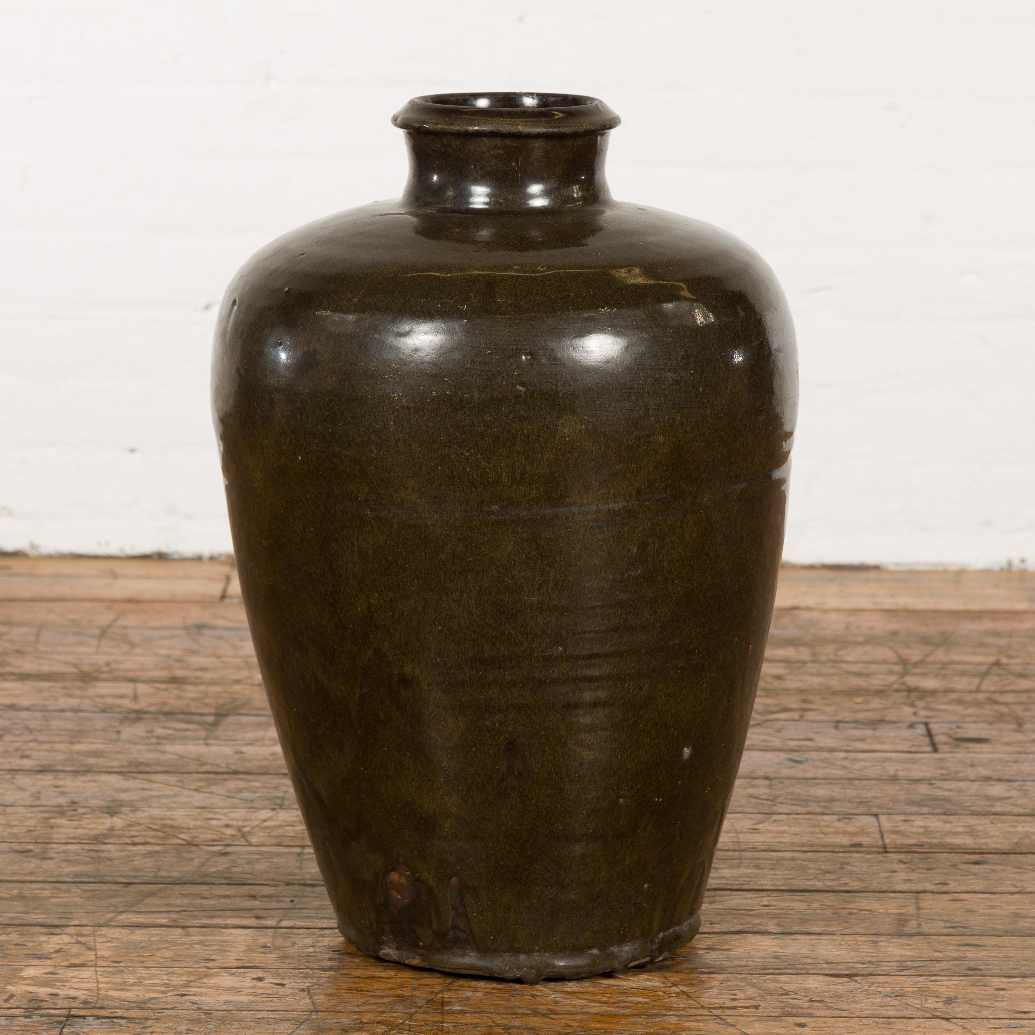 A vintage dark brown/green glazed ceramic storage jar. Evoking a bygone era of artisan craftsmanship, this vintage ceramic storage jar is a testament to the beauty of functional design. Bathed in an elegant dark brown hue, the jar possesses subtle