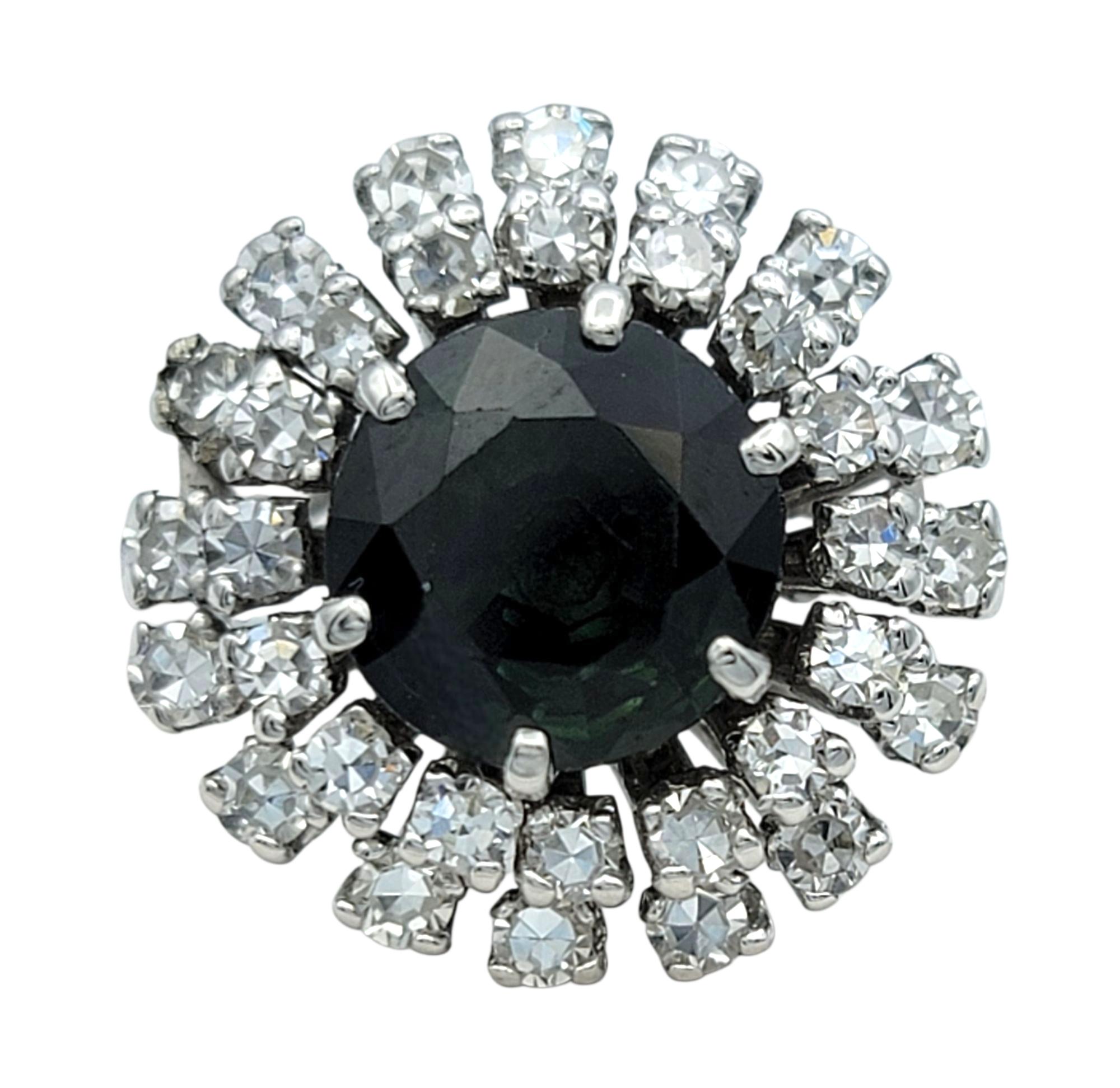 Ring Size: 7

This dramatic sapphire and diamond ring captivates with its vintage charm. A round cut 2.47 carat dark green sapphire anchors the center, bursting outward with a double halo of sparkling single-cut diamonds arranged like radiant