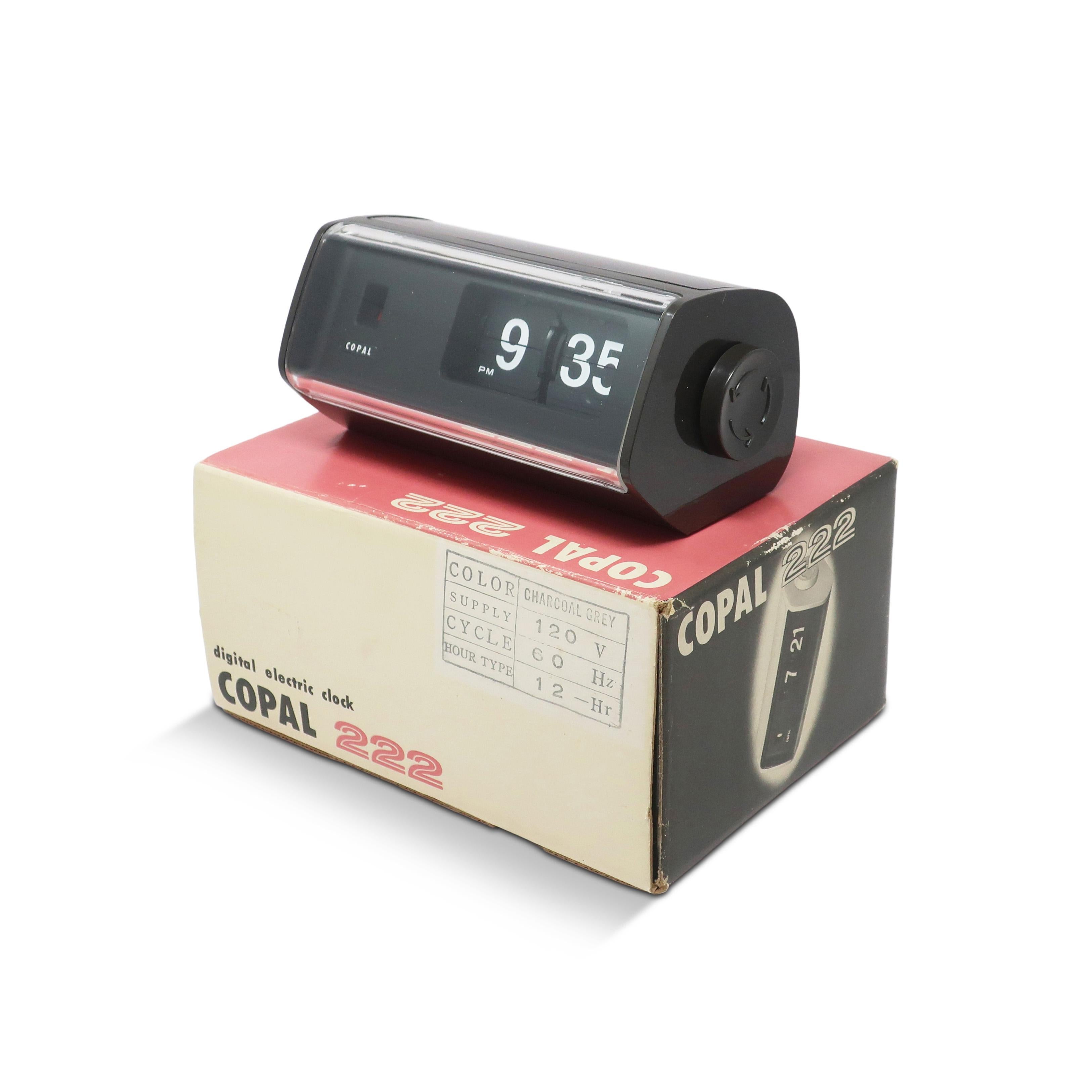 Un bellissimo Copal Clock modello 222, moderno e di metà secolo, con cassa in plastica grigio scuro, quadrante nero e frontale in plastica trasparente. I minuti e le ore scorrono con il passare del tempo, offrendo un suono soddisfacente e