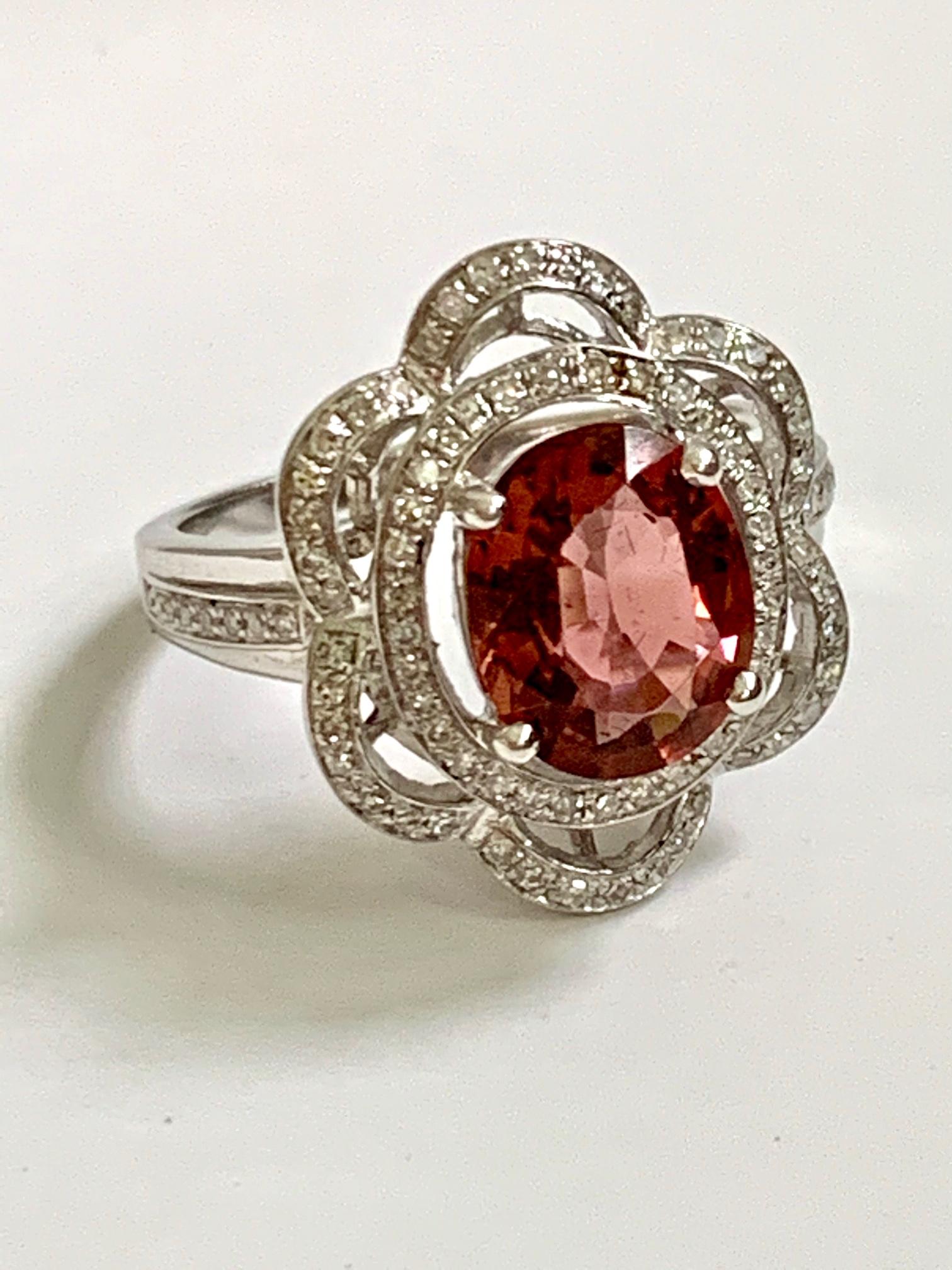 This is a beautiful vintage 14k white gold ring with a large oval faceted tourmaline. This stone is dark red; almost brownish red in color. The gemstone is surrounded by a flower halo of diamonds.

The stone is 2.5ct.  The diamonds total