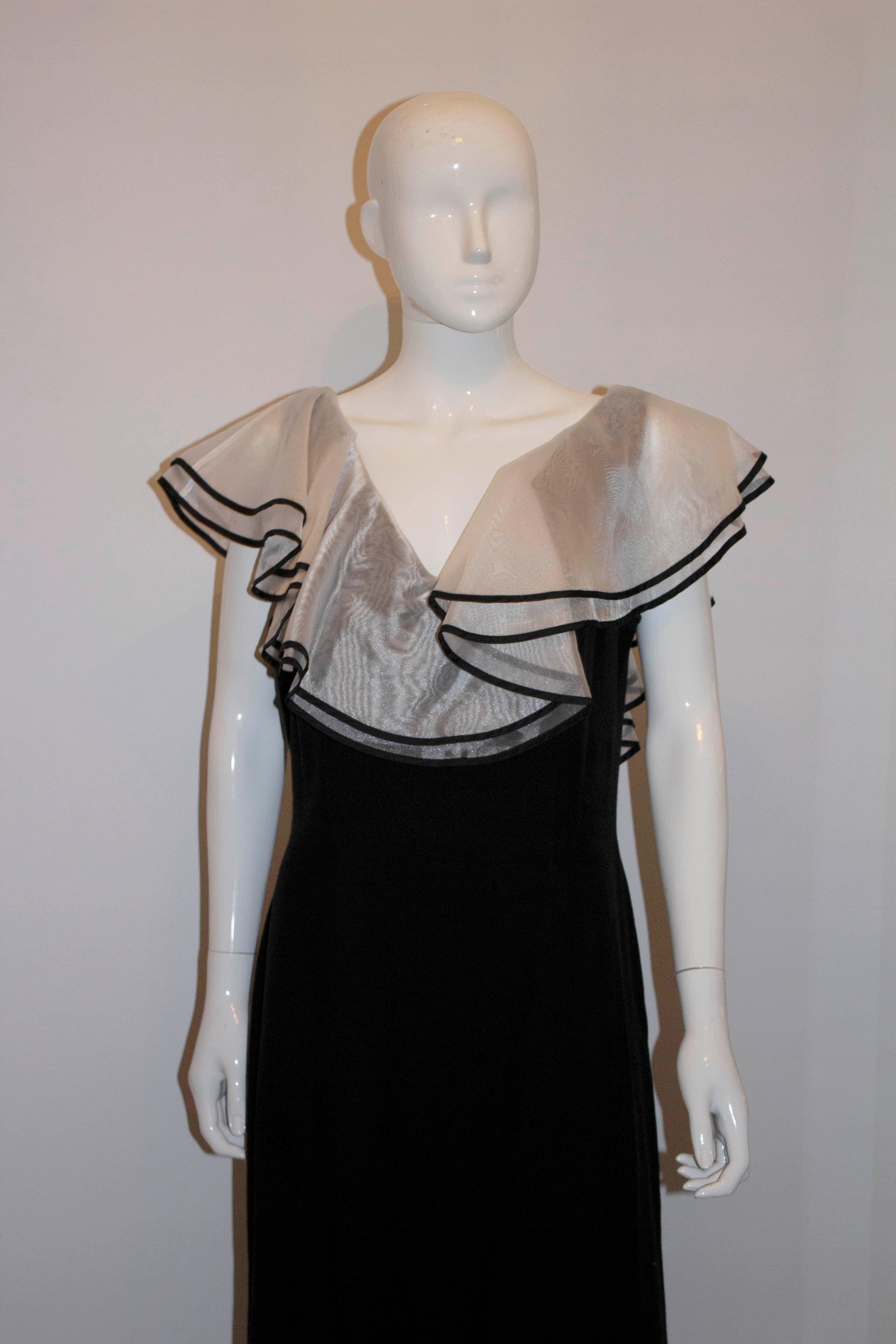 A vintage David Butler evening gown , in black crepe with a double layer organza frill.   The dress has a v neckline front and back and the frill sits off the shoulder.  The dress is fully lined and has a 22'' back slit. 
Measurements Bust 40'',