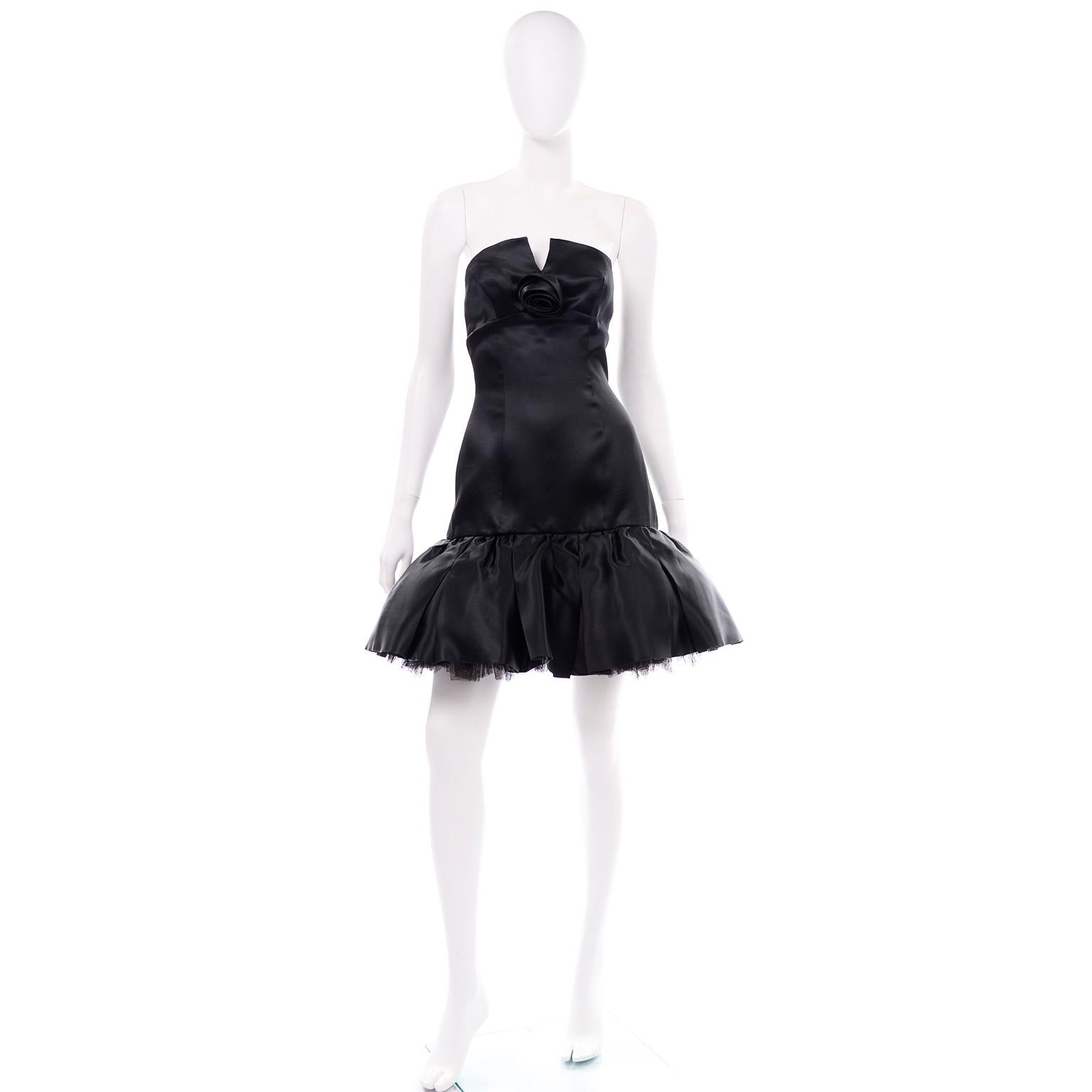 This beautiful soft black silk satin vintage David Fielden dress has a tulle petticoat for fullness and a round strapless with a small v-cut down the center. There is an empire waistline and a center focus is the satin silk rose. There is metal