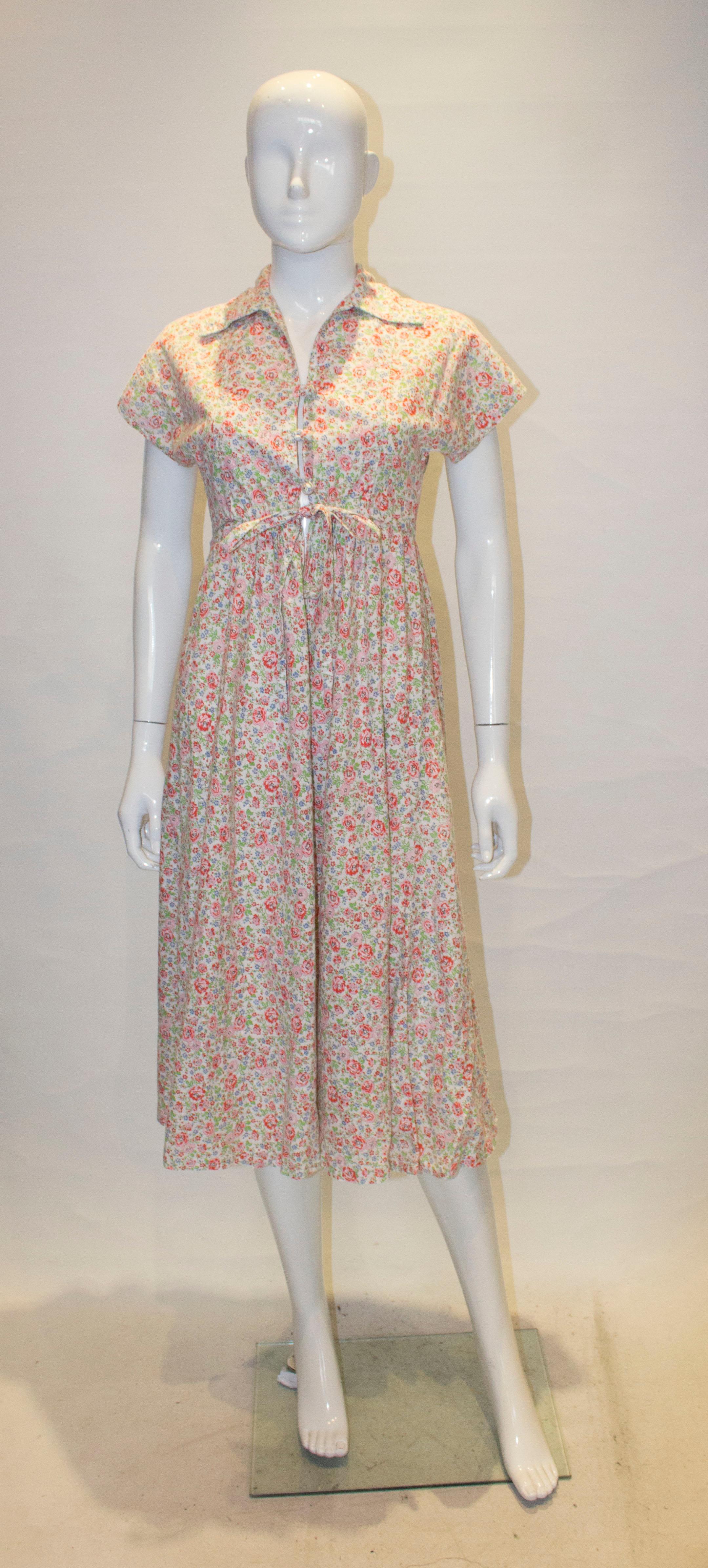 A pretty vintage cotton dress  by David Silverman.  The dress has a  fabric covered button opening at the front with a drawstring waist.,measuring from 25'' - 28'' , and cap sleeves.