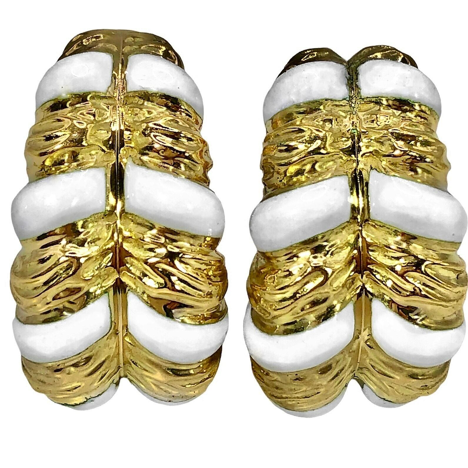This striking pair of textured, 18k yellow gold David Webb earrings is punctuated with five rows of white enamel stripes. These comfortable to wear, 
medium size, half hoops measure 1  inch in length by approximately 5/8 inches at the widest point.