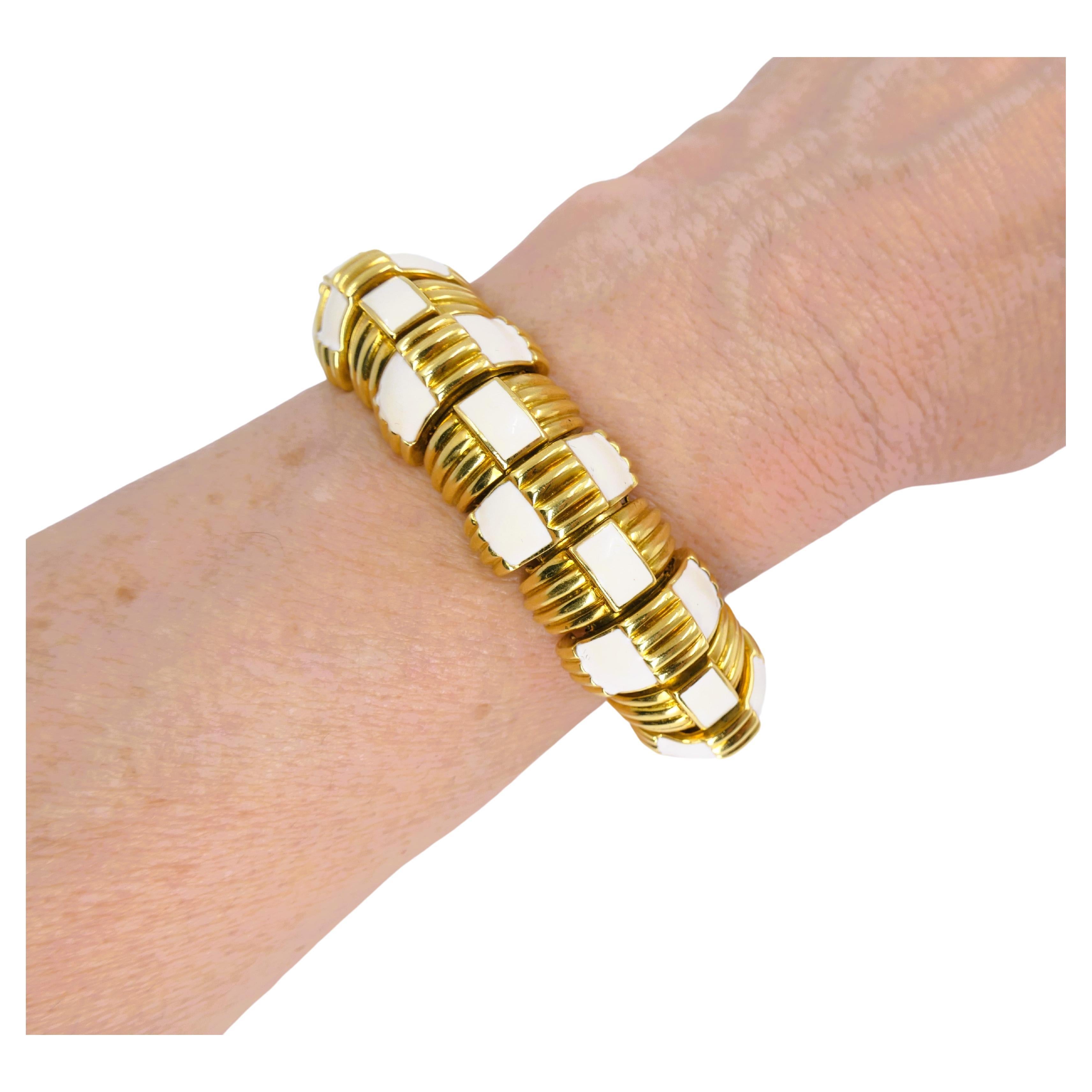 A gorgeous David Webb 18k gold bracelet with white enamel.
The bracelet is crafted out of the hemispheric sections that are invisibly connected to create a flexible bracelet. The gold sections alternate with the painted enamel pattern. Ribbed