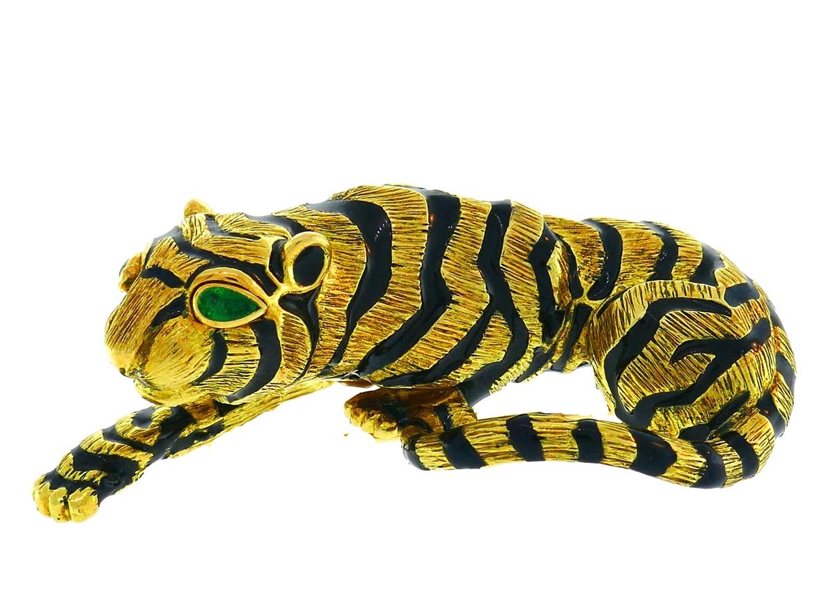 Bold and chic signature David Webb tiger pin created by in the 1970's. 
Made of 18 karat (stamped) yellow gold and black enamel; the tiger's eyes are accented with pear shape emeralds (approximately 0.20 carat total weight).
Measurements: 2-3/8 x