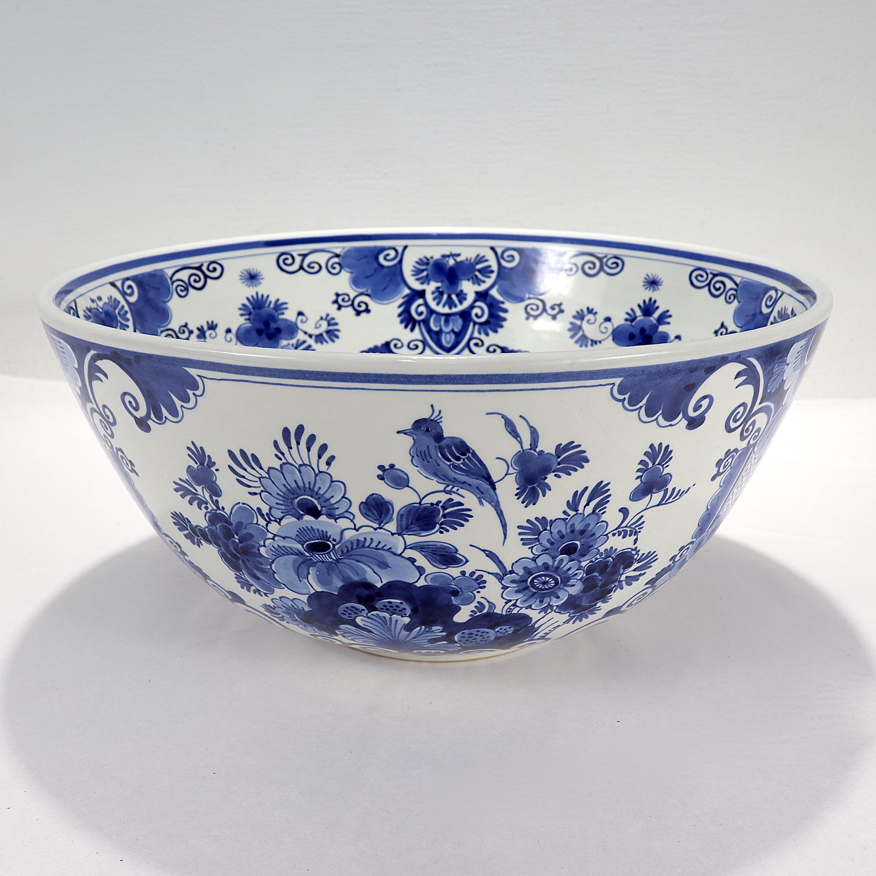 A fine vintage Delft pottery punch bowl. 

By De Porceleleyne Fles (aka Royal Delft).

Painted by L. de Groot.

Decorated throughout with typical Delft floral & fruit motifs along with a single bird.

Bearing a factory label to the