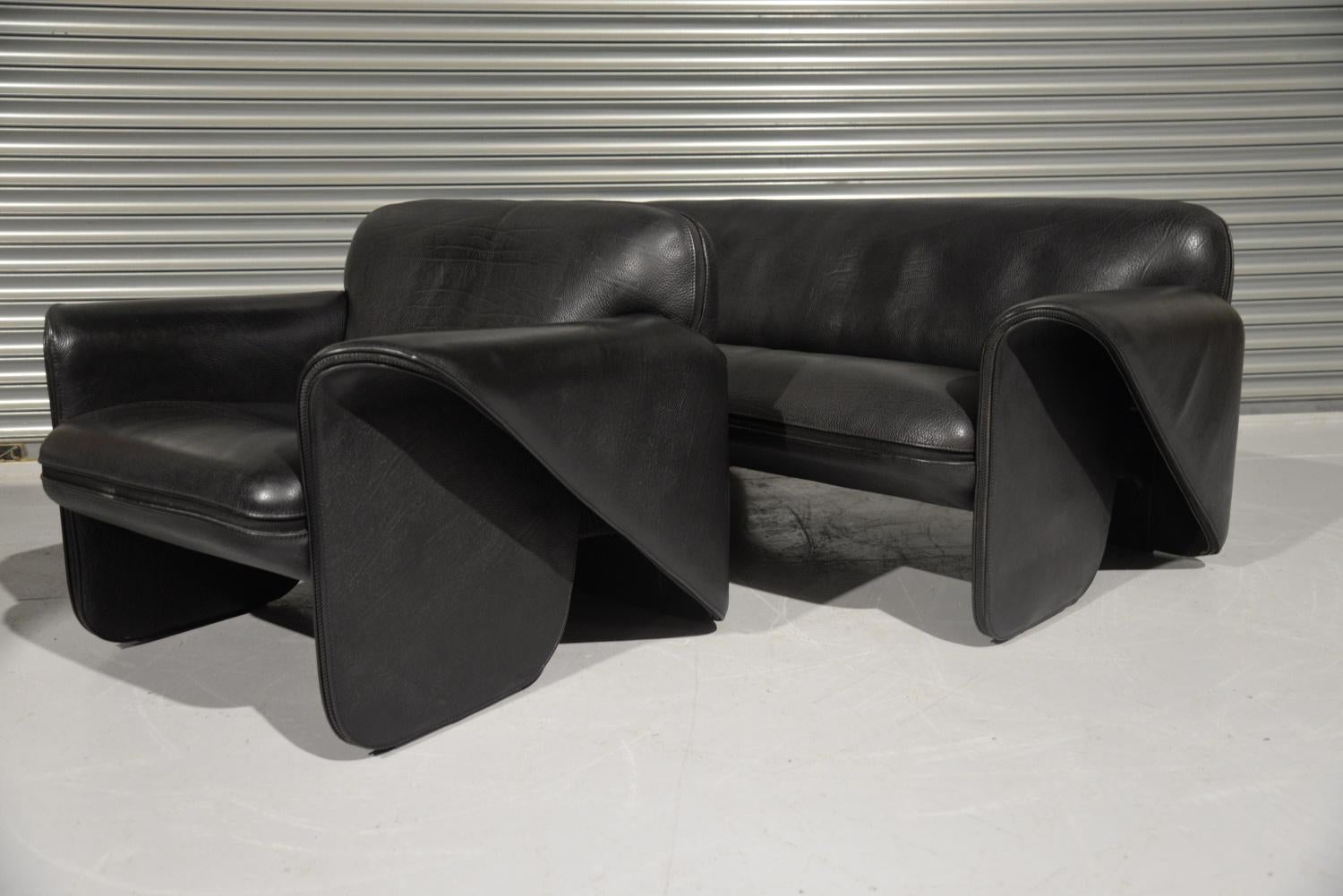 We are delighted to bring to you an ultra rare vintage De Sede DS 125 sofa and armchair designed by Gerd Lange in 1978. These sculptural pieces are upholstered in 3mm-5mm stunning thick black leather with a decorative zipper seam. Rarely available