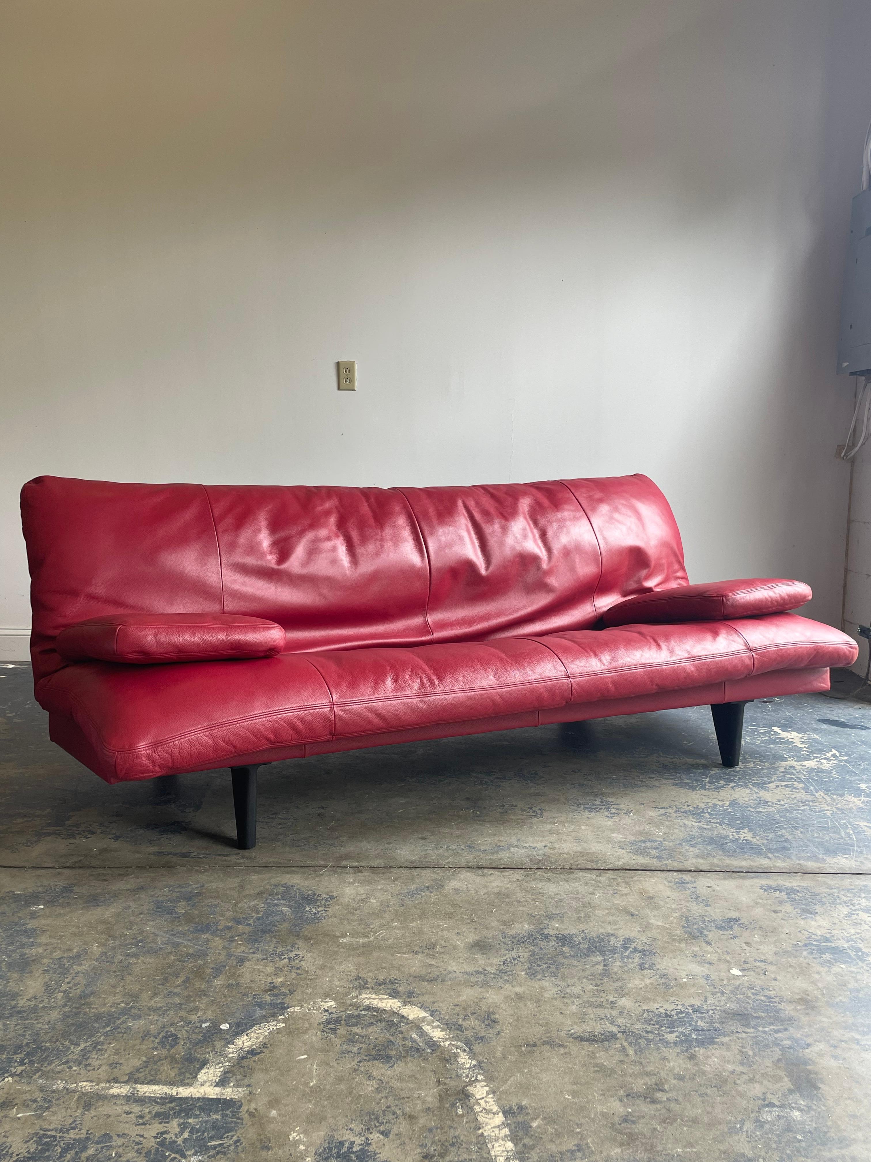 Unique and uncommon sofa designed by Ernst Ambühler for De Sede circa 1980s. Features thick, soft red leather, and metal legs. The back on this folds flat in conjunction with the pivoting back legs to transform from a sofa into a daybed. Cushion can