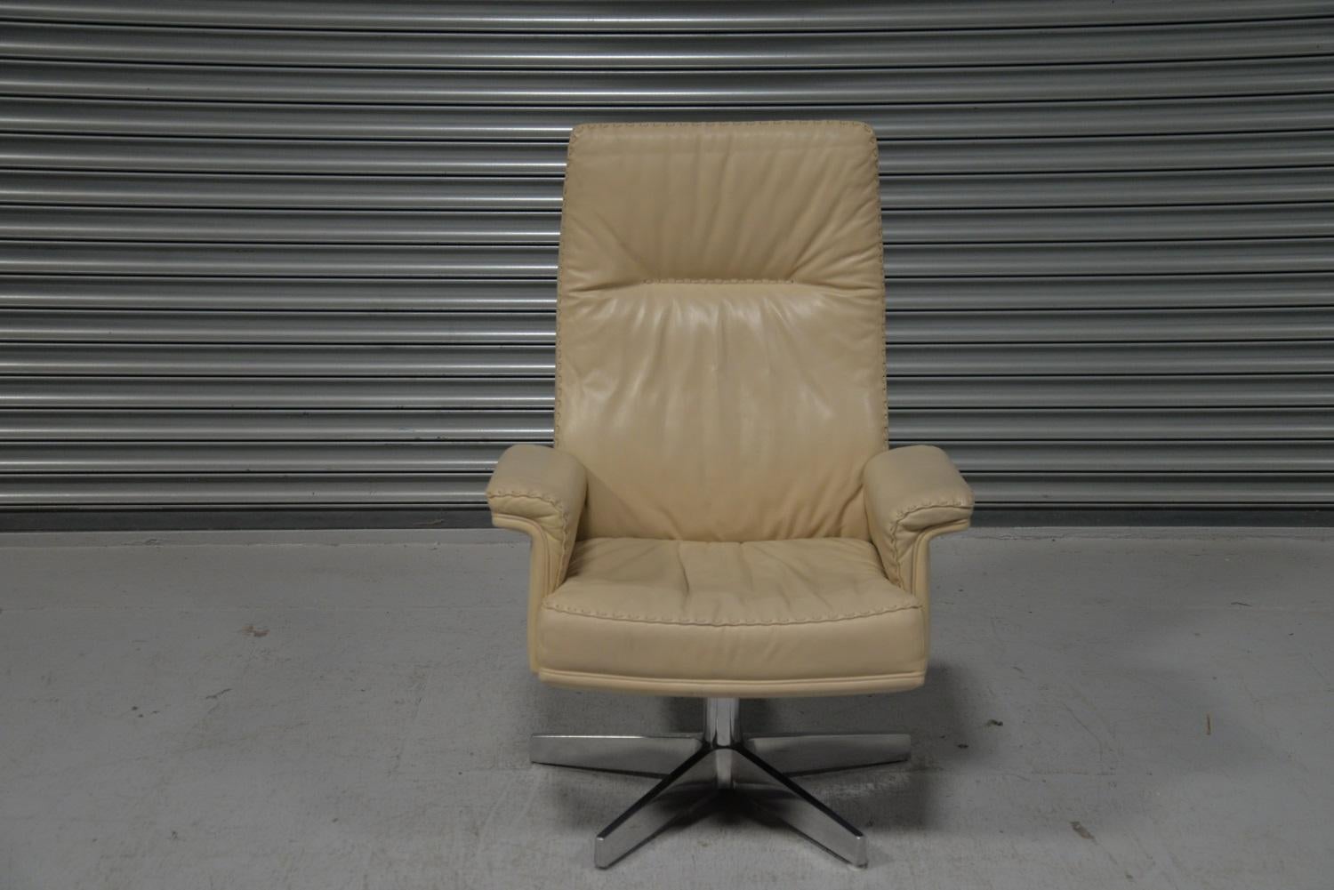 We are delighted to bring to you a vintage 1970s De Sede DS 35 high back leather swivel armchair with ottoman. Hand built in the 1970s by De Sede craftsman in Switzerland, the armchair is upholstered in soft cream aniline leather sitting on a