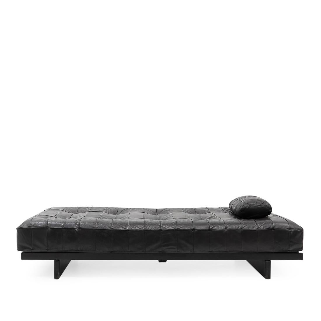 De Sede Daybed model DS-80 in beautifully patinated leather, featuring one pillow. 

The leather is a patchwork design made from black pigmented aniline leather, which typically gives a very “lived” look due to the open nature of the material. The