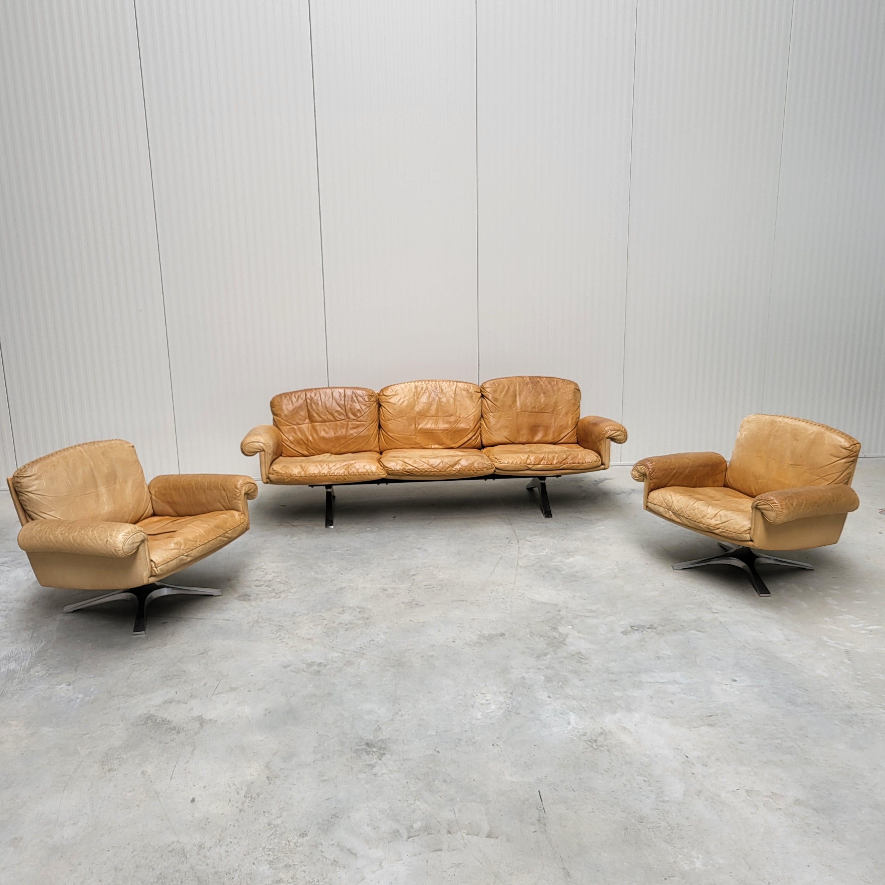 This amazing living room set with a 3-seater Sofa and 2x lounge chairs model DS31 were designed in the 1960s by the De Sede design team and produced by De Sede in Switzerland in the 1970s. 

The living room set features an amazing patinated cognac