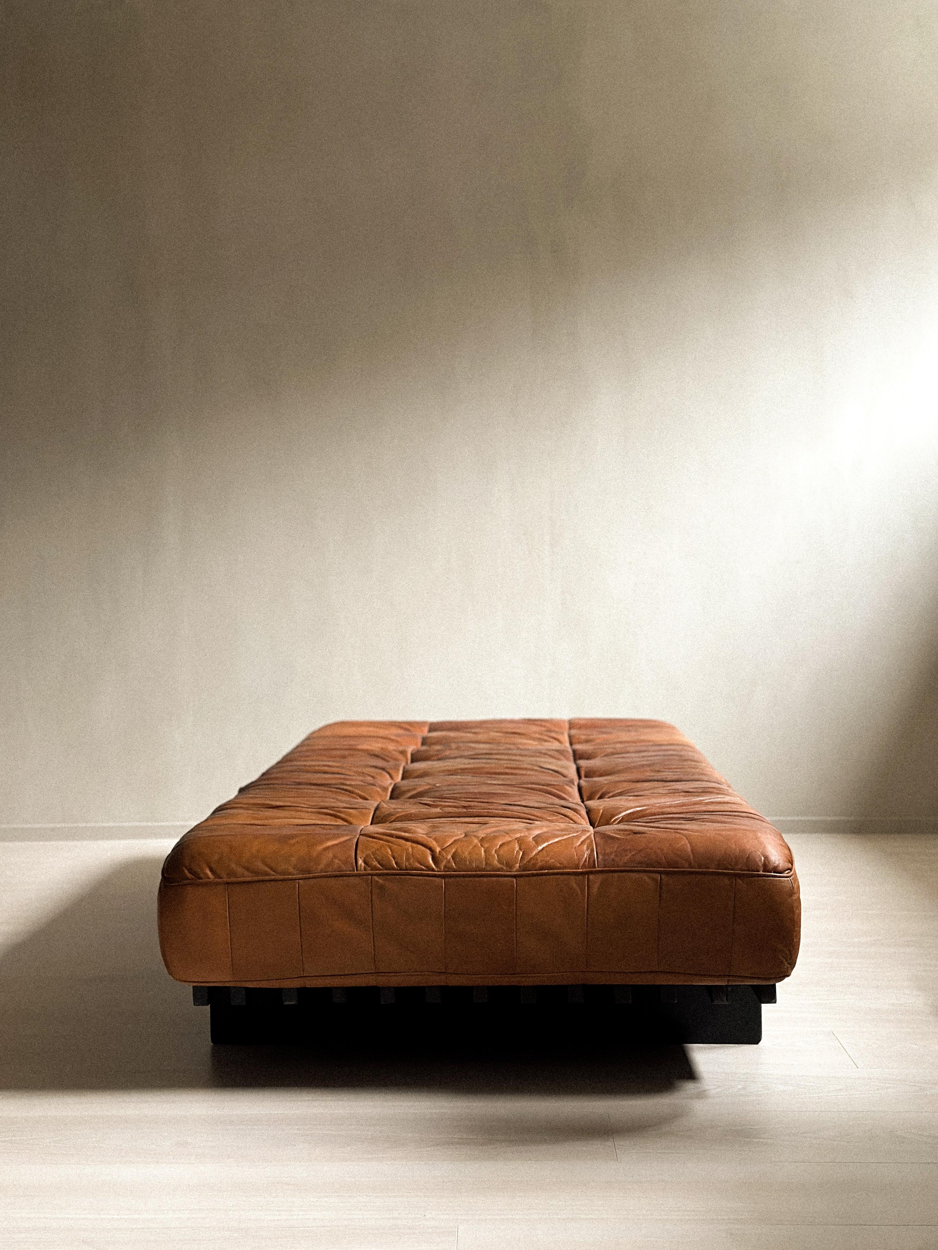 A vintage De Sede DS80 Patchwork Daybed in cognac leather and ash, Switzerland 1970s. 

Signature patchwork leather has wonderful patina and sits on a black slatted wood frame in ash. Wear consistent with age and use. Small tears, marks, stains.