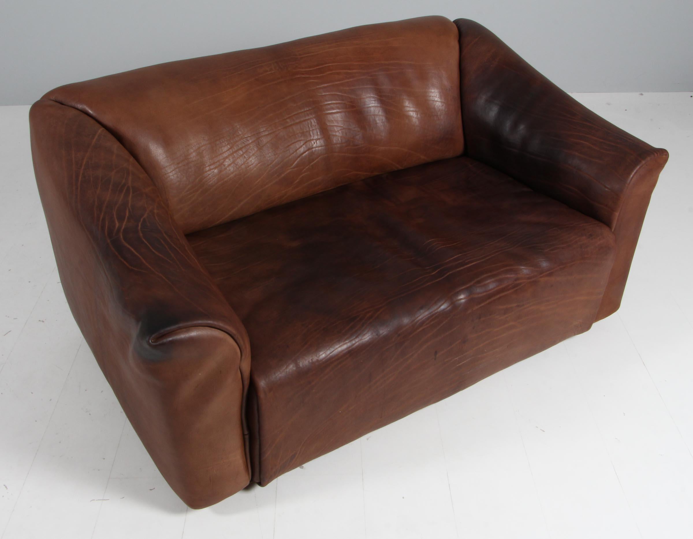 Canapé très confortable DS47 en cuir patiné par De Sede. Le design est simpliste, mais très moderne. L'extérieur étroit et cubique et l'intérieur doux et incurvé soulignent le caractère confortable de cet ensemble. Le cuir épais est posé en une