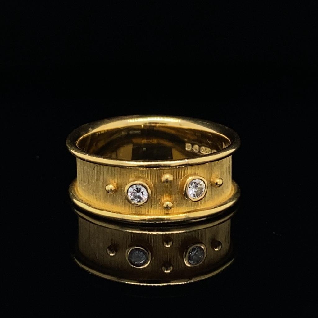 A vintage De Vroomen diamond set 18 karat yellow gold ring.

The satin finished diamond ring in 18 carat yellow gold with raised polished edges, comprised of two collet set round brilliant cut diamonds set between four equally spaced gold