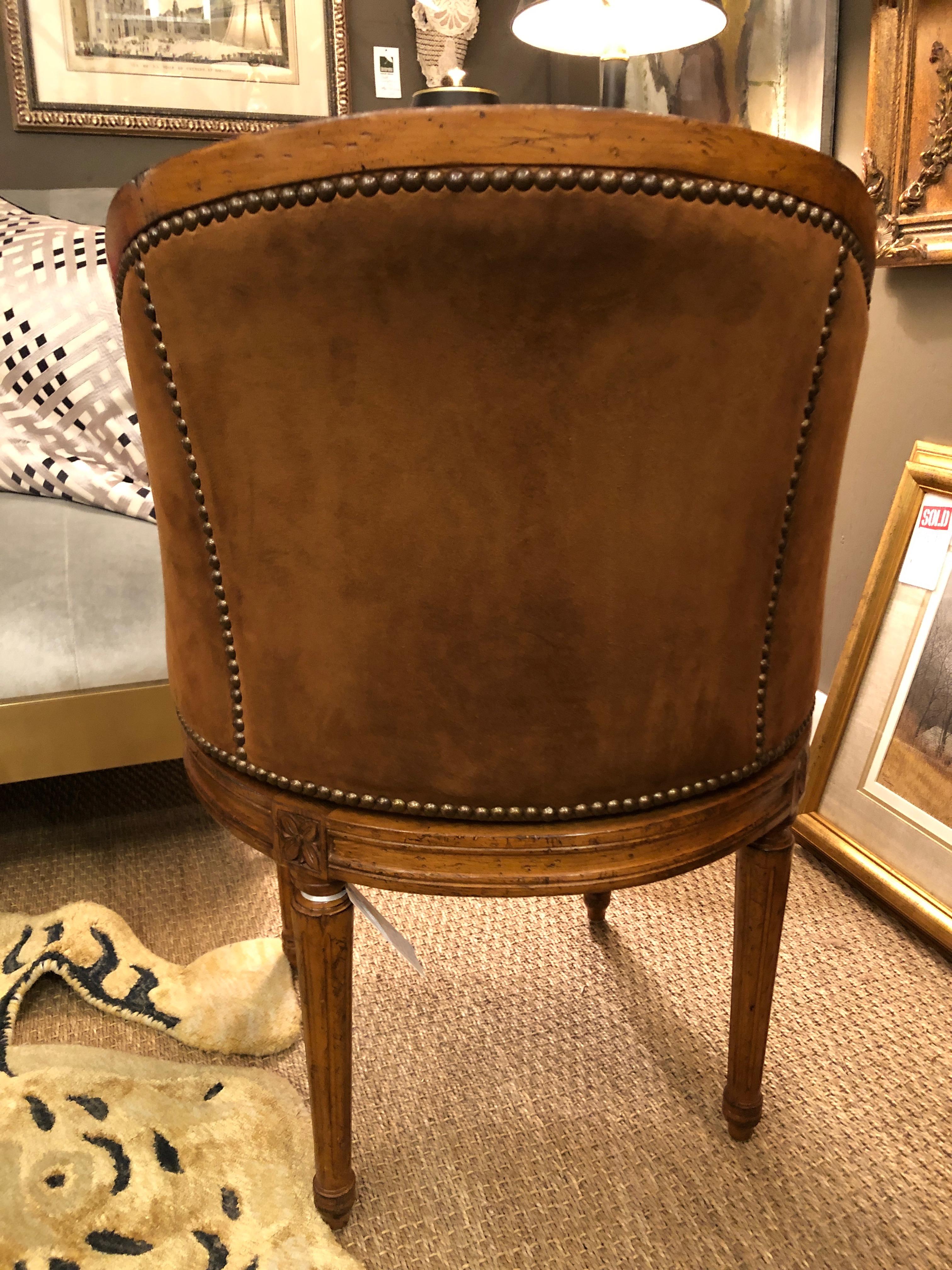 A suave compact beautifully made walnut swivel barrel chair, stunning from every angle, upholstered in black leather on the front, soft brown suede on the back, and finished with brass nailheads.
The legs are tapered and reeded and there is